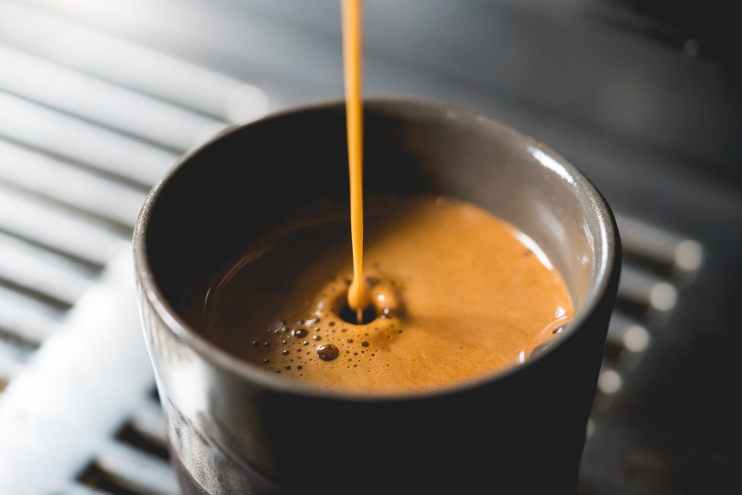 Close-up of espresso pouring into a cup from a coffee machine