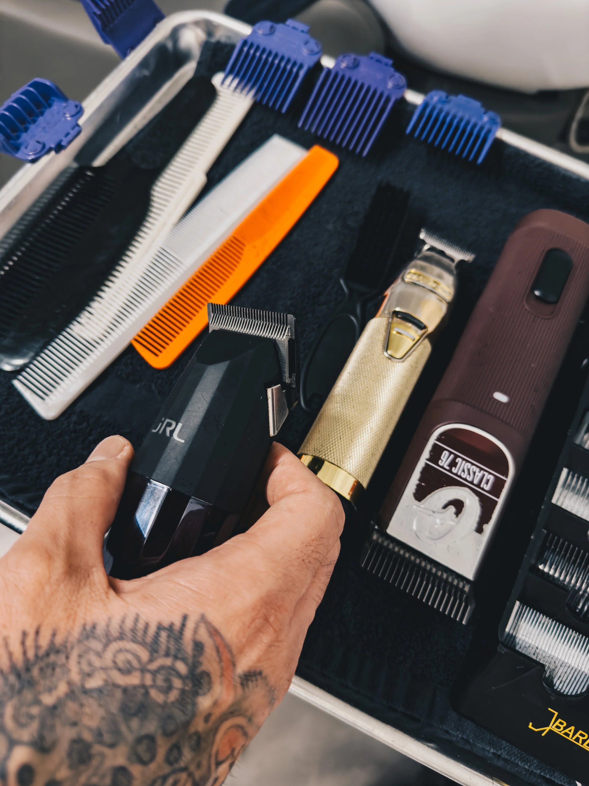 tattooed hands holding barber tools clippers