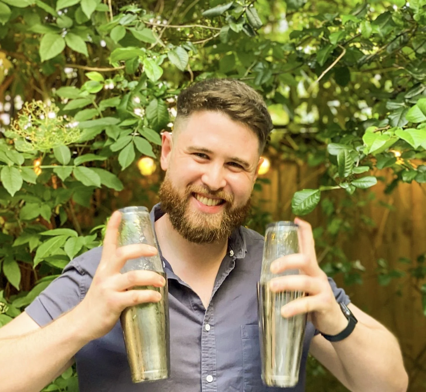 A close up of a smiling bartender shaking cocktails at a garden party in Sussex