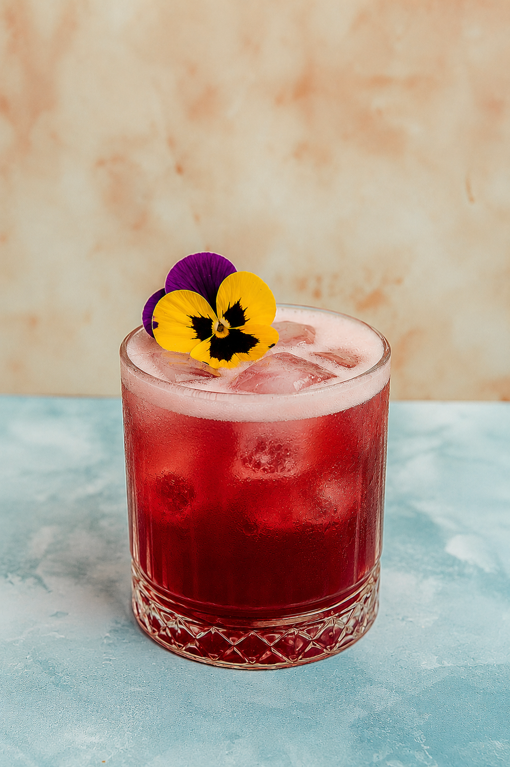 Hibiscus Gin Sour cocktail in a coupe glass garnished with dried hibiscus flower