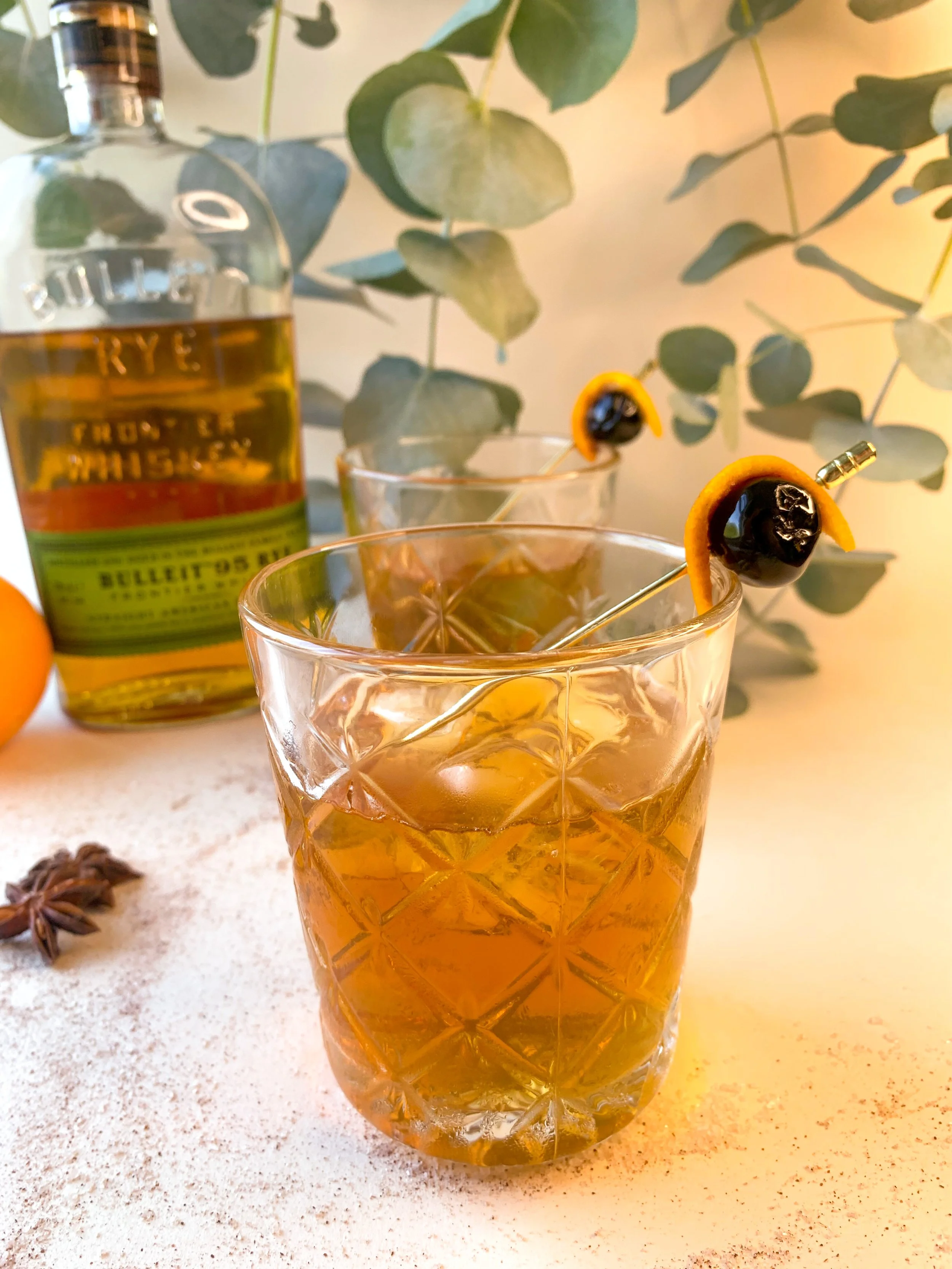 An old fashioned cocktail served in a rocks glass garnished with a maraschino cherry and orange rind