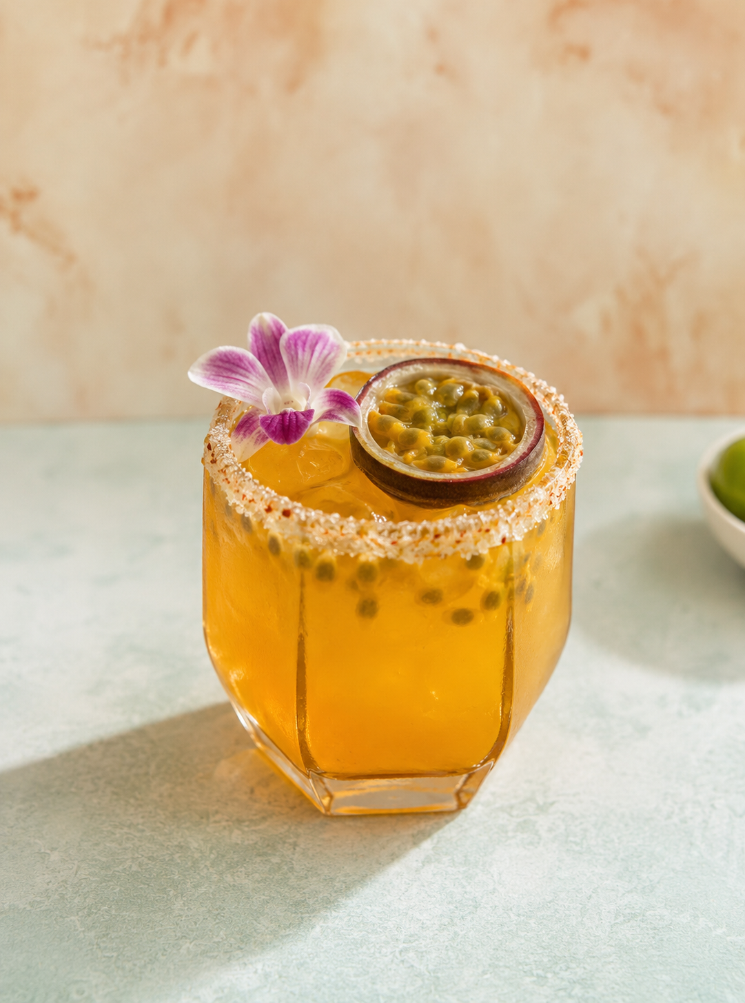 A spicy passionfruit margarita served in a rocks glass garnished with half a passionfruit and an edible flower