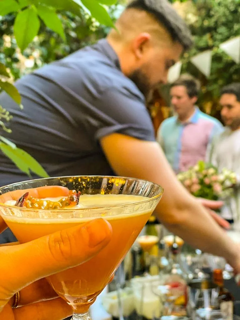 A pornstar martini being raised to a premium cocktail bartender in a garden party celebration in Sussex