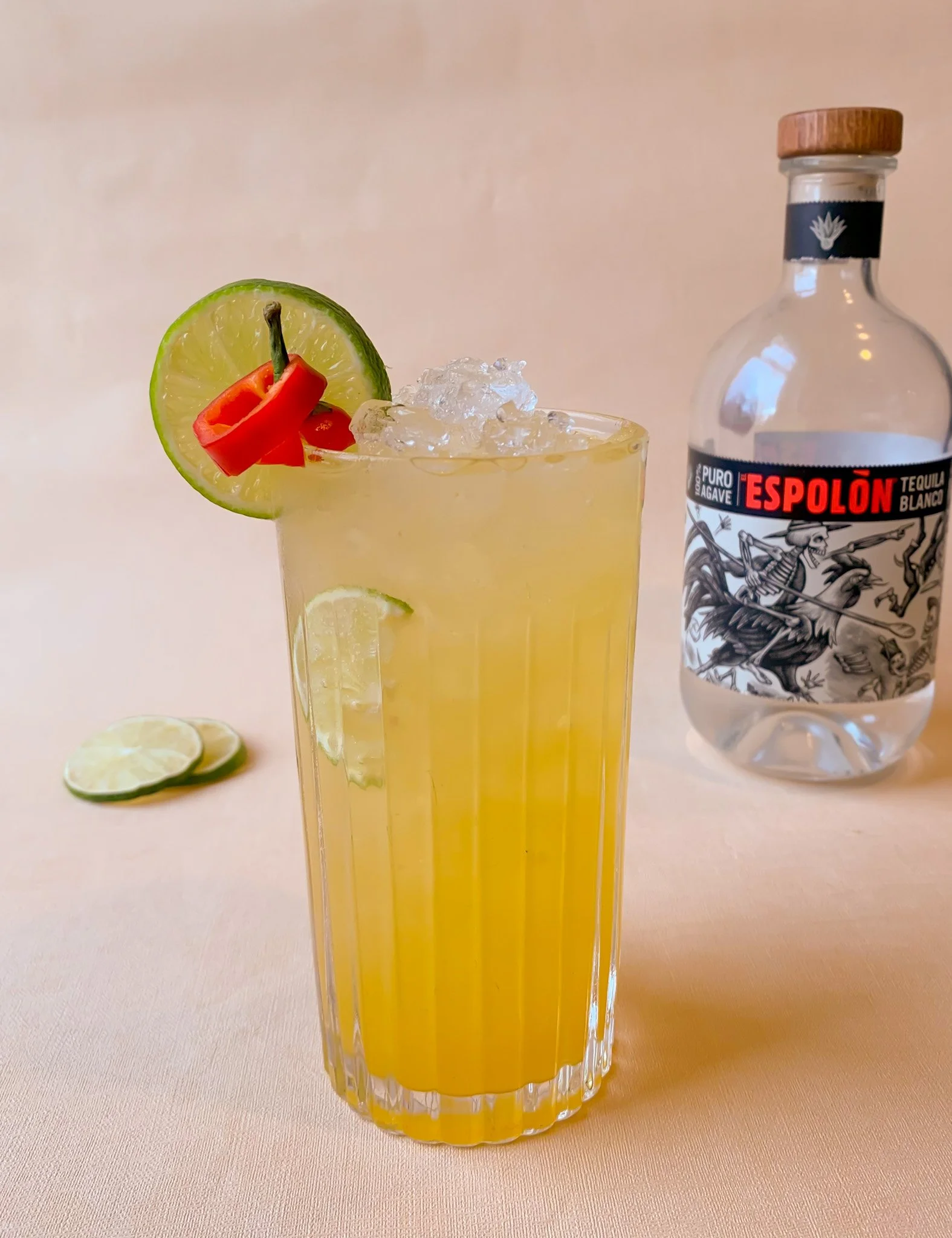 A Mexican Mule cocktail served over ice in a highball glass garnished with a lime wheel and red chill slices