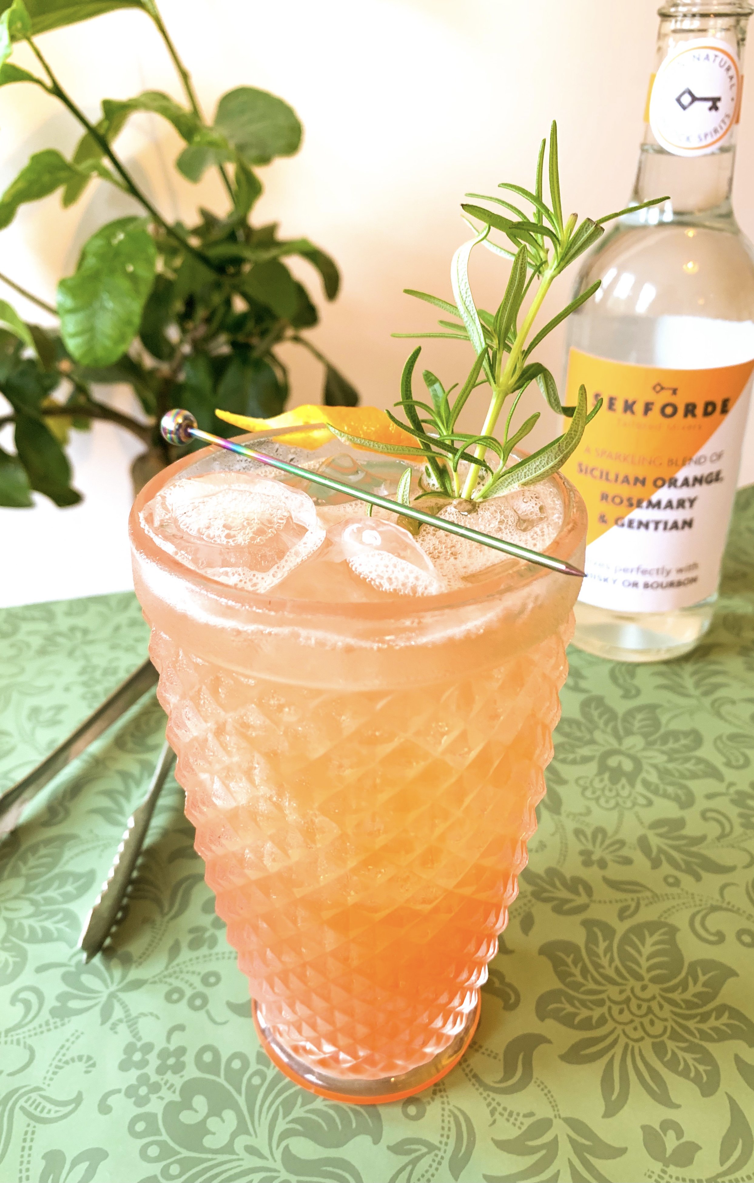 Sicilian Paintbrush cocktail in a highball glass garnished with rosemary and orange rind