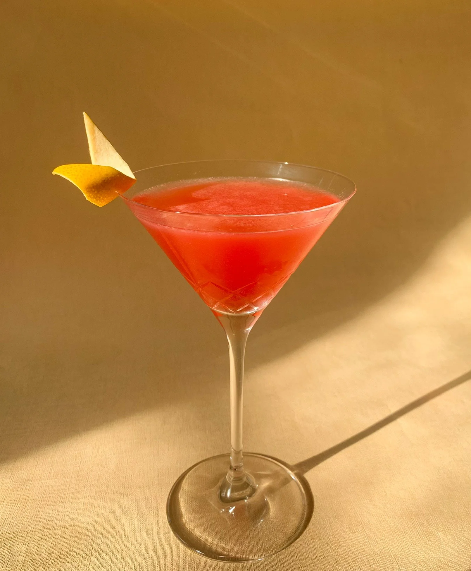 An Old Amigo cocktail served in martini glass with an orange twist garnish