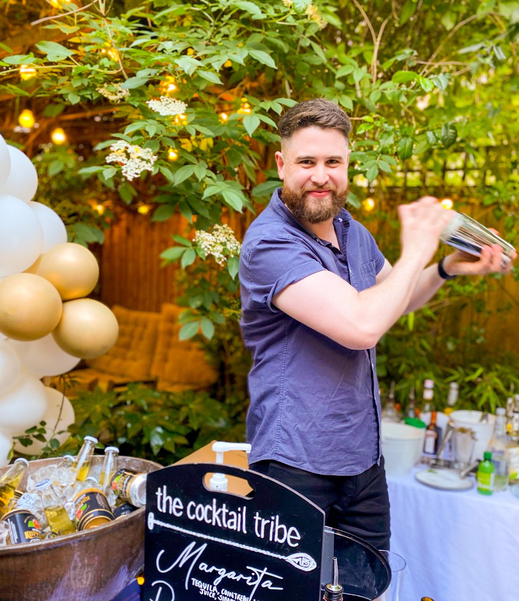 A bartender shaking a cocktail for an engagement party in a garden in Lewes