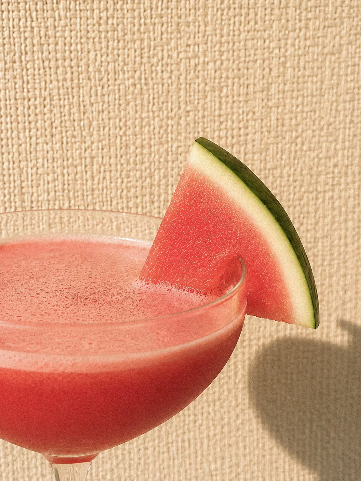 A Miami Martini cocktail close up served in a modern coupe glass and garnished with a wedge of watermelon