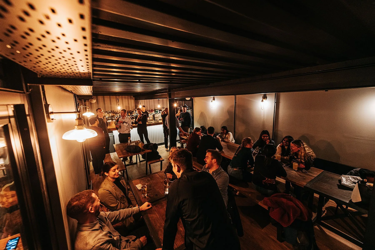 People socializing and drinking at a bar in a dimly lit restaurant or pub