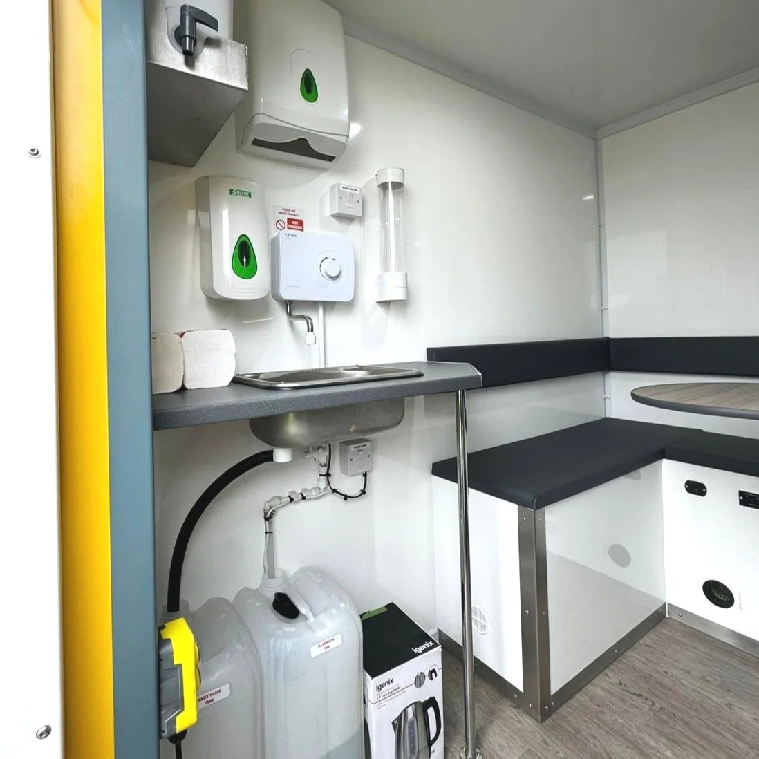 Cleaning station with soap dispensers, paper towels, a sink, a sanitizer, and a UV sterilizer light in a medical or laboratory setting.