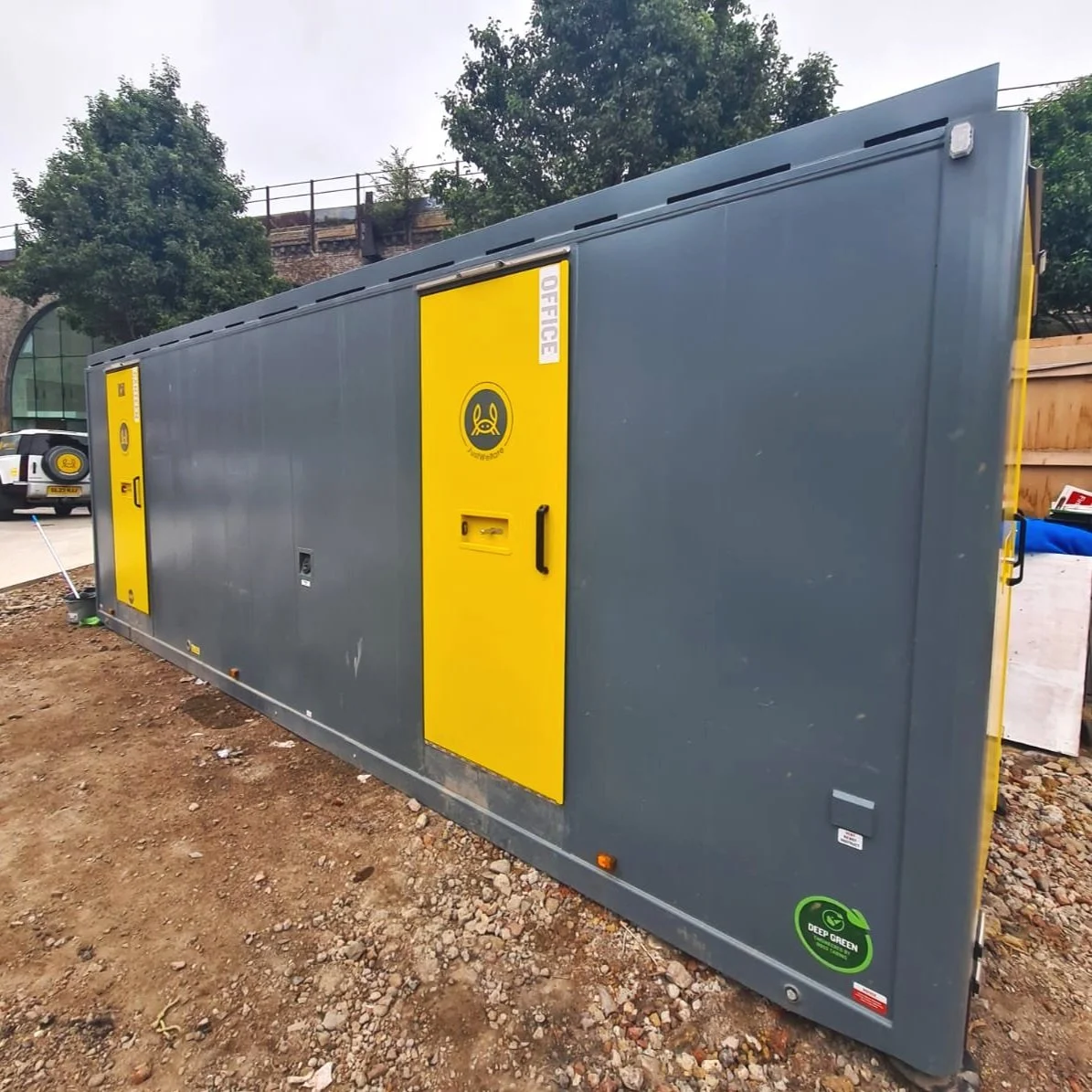 Large gray utility container with yellow doors labeled 'OFFICE' and a green sticker indicating 'DEEP GREEN.''