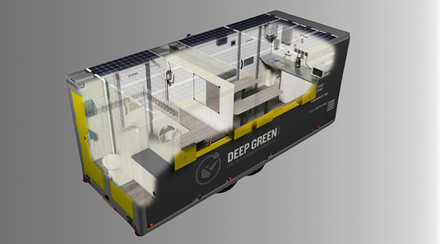 A detailed model interior of a mobile smart building with solar panel roof, labeled "Deep Green," containing office and living spaces, including a kitchen area, desks, and a bathroom.