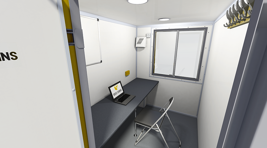 Small, plain office with a gray desk, a black chair, a window, and a laptop on the desk.