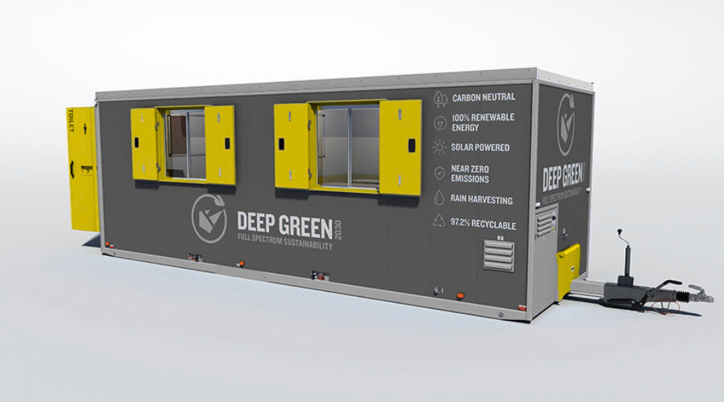 A mobile tiny house with solar panels, yellow window shutters, and eco-friendly features, branded with 'Deep Green 2030,' emphasizing sustainability and renewable energy.