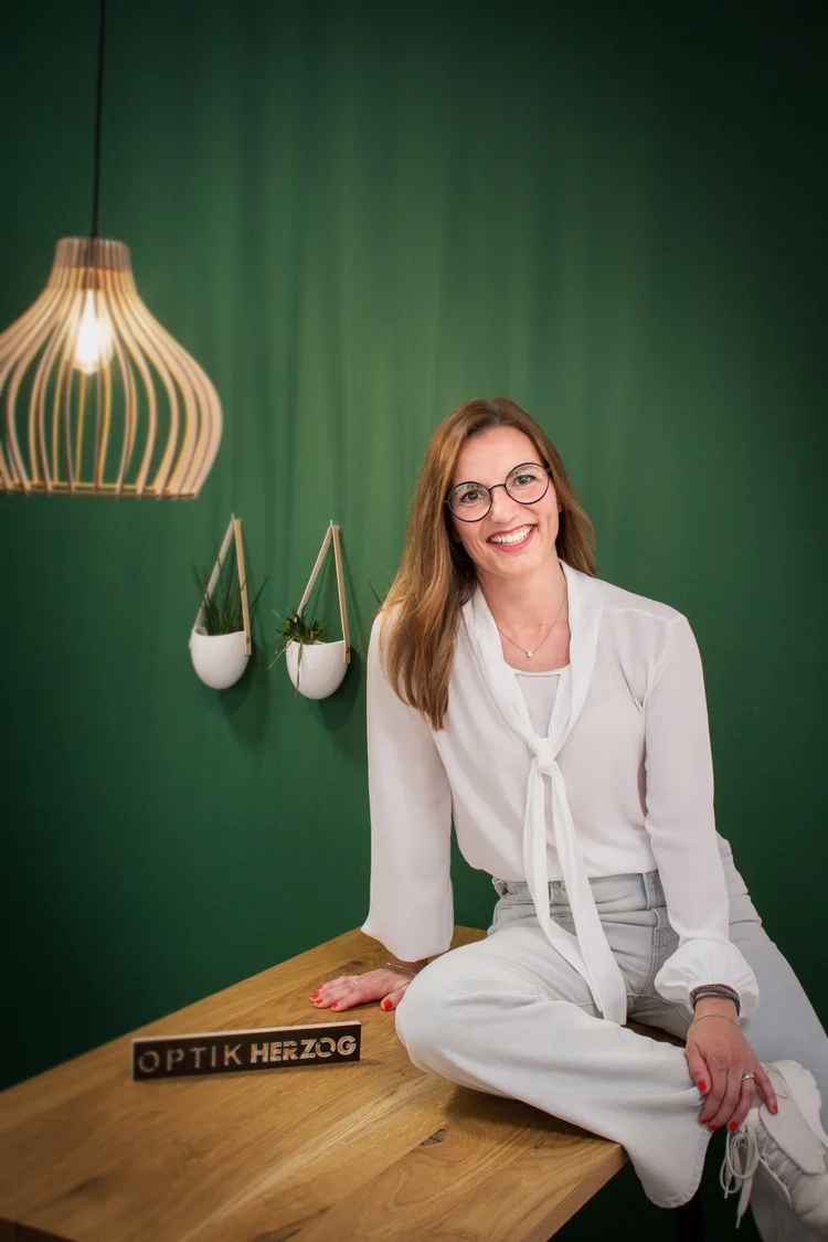 Christine Henle, Augenoptikermeisterin, lächelnd vor grüner Wand