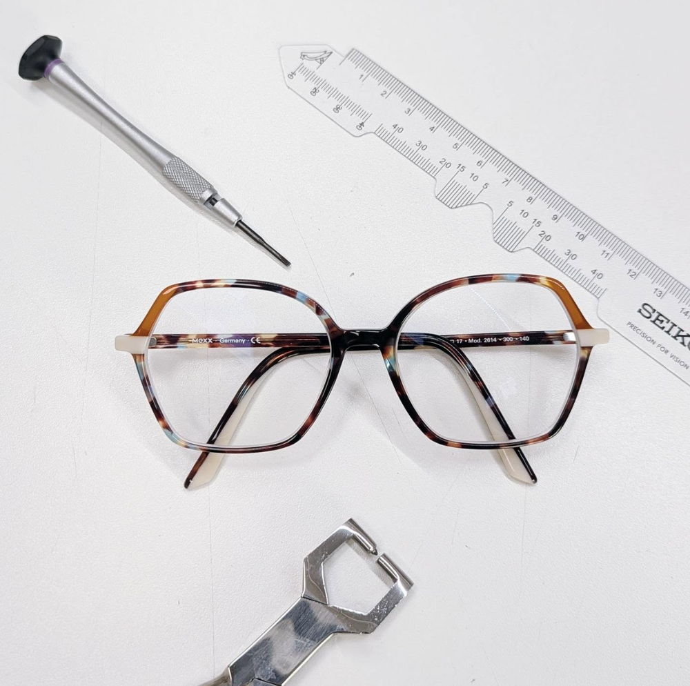 Brillenfassung mit Pupillometer, Schraubendreher und Zange auf dem Werktisch
