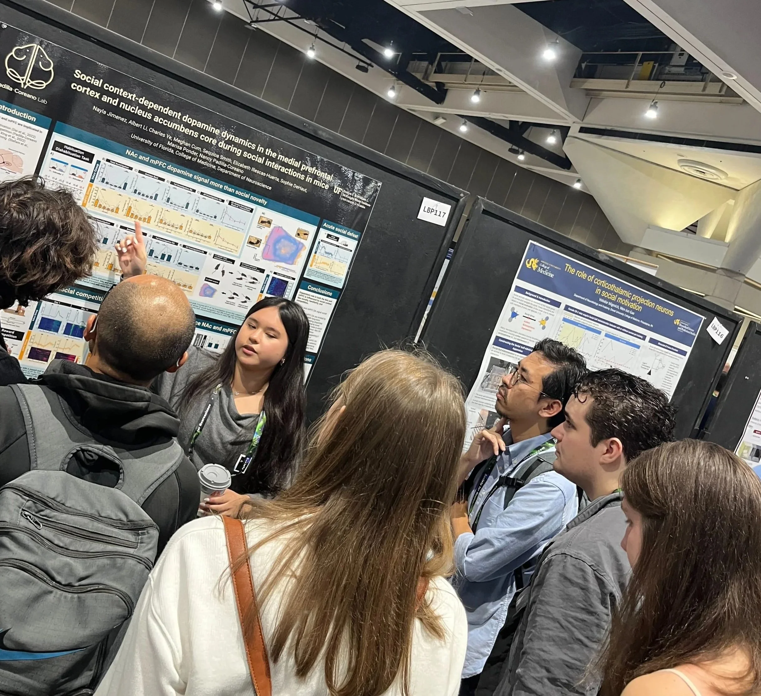 Action shot of Nayla discussing her social context-dependent dopamine dynamics data poster with the audience at SfN