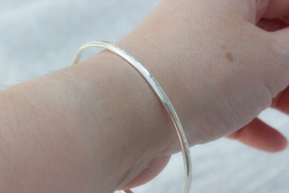 slim textured silver bangle worn on wrist of woman