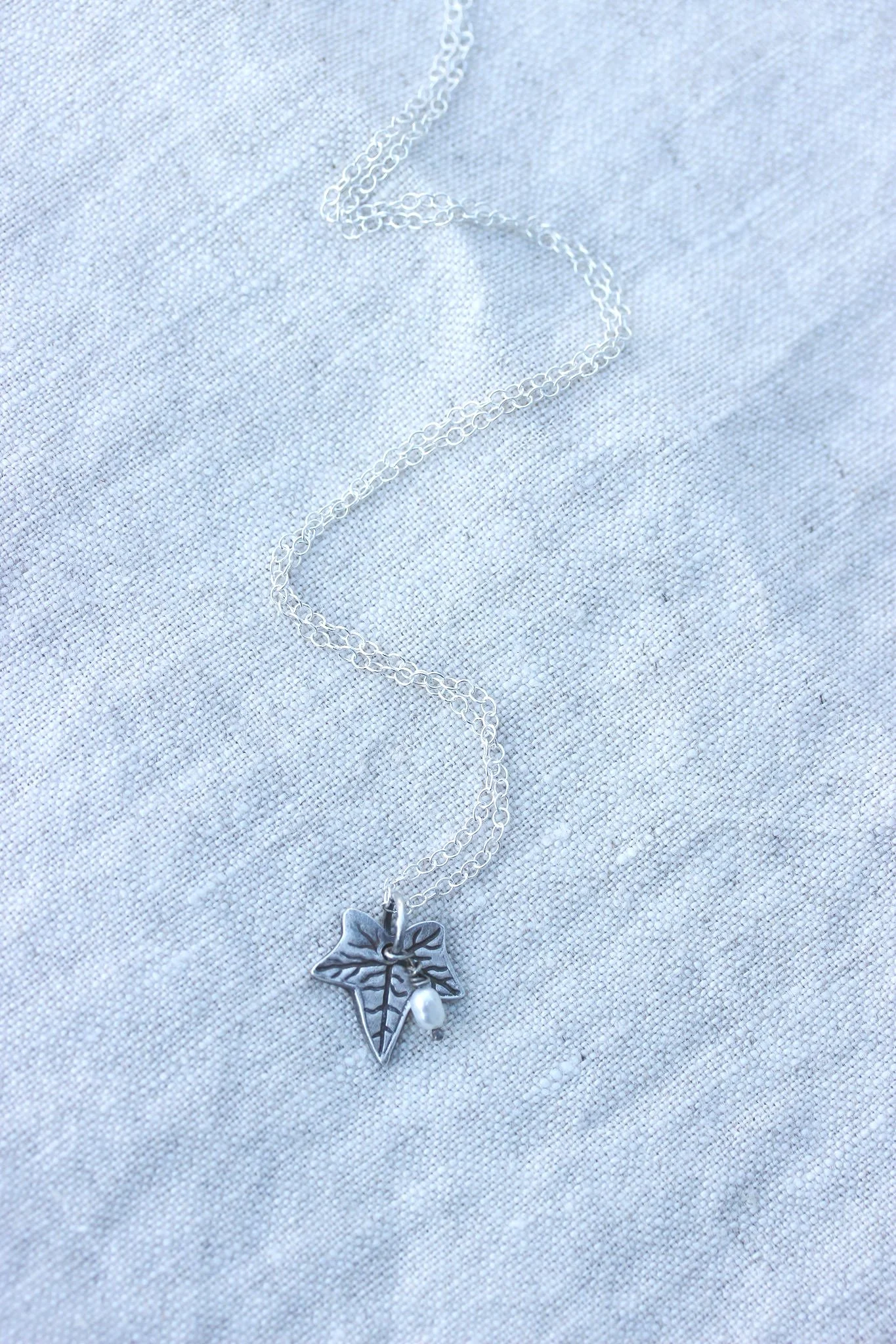 A small silver ivy leaf pendant necklace with freshwater pearl charm bead on silver chain by the little red hen jewellery