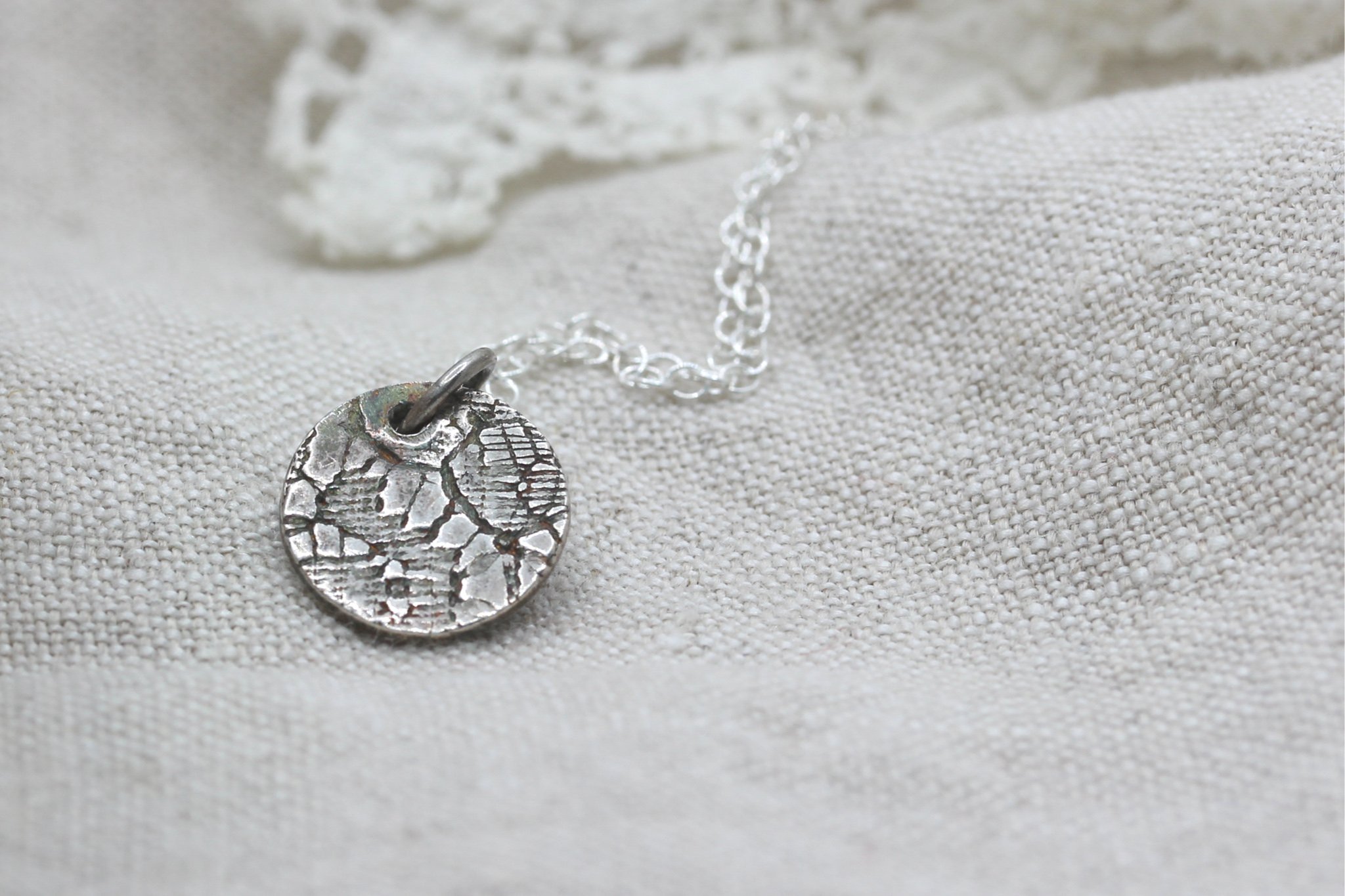 Silver circle pendant with lace pattern on silver chain