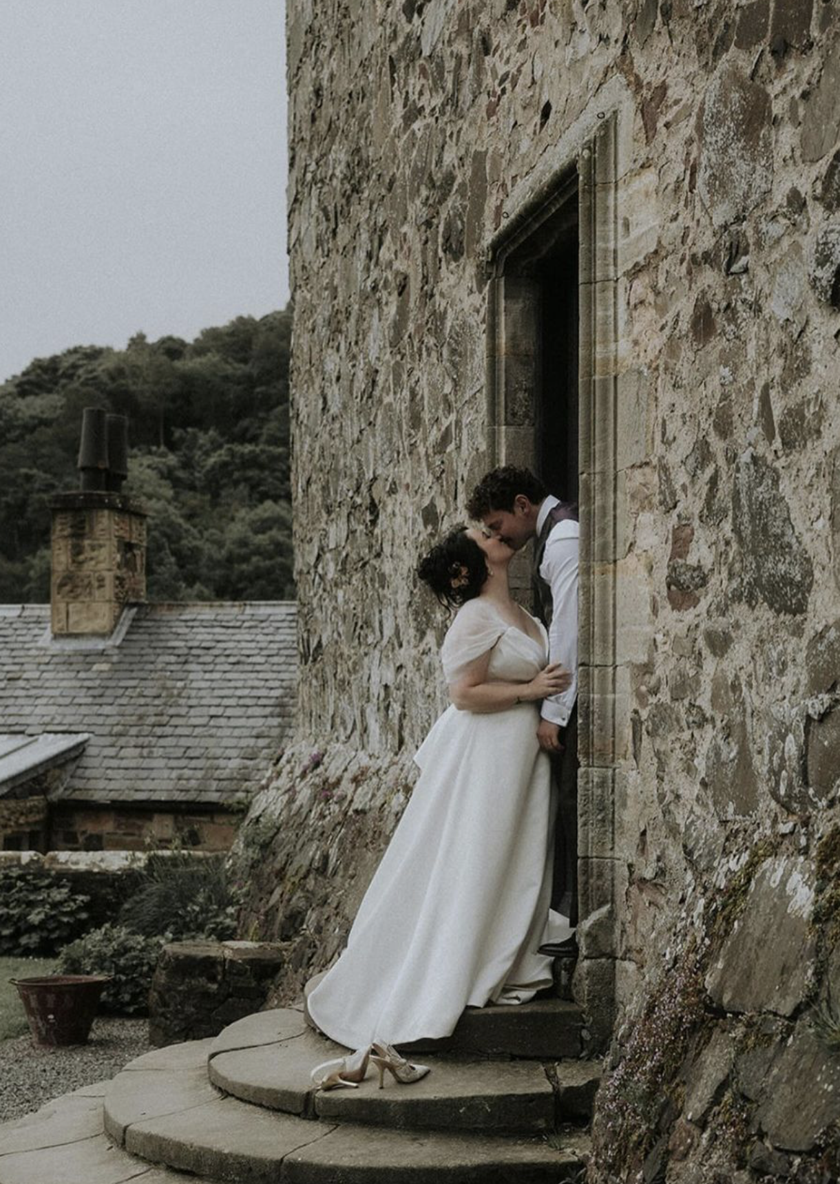 Bride and groom kissing in a stone doorway