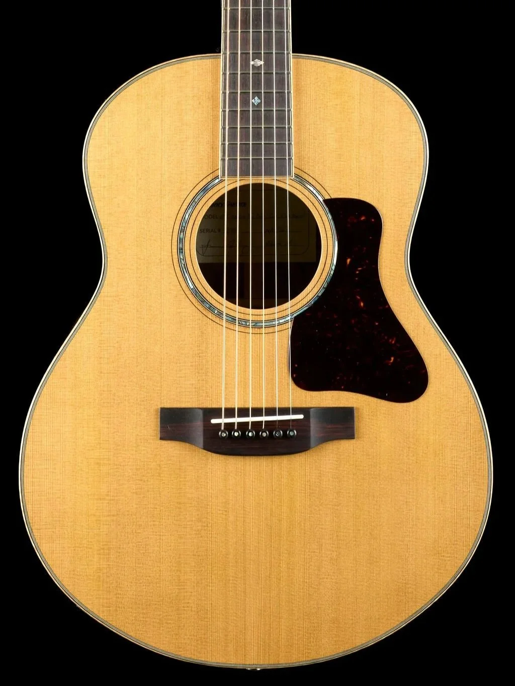 Close-up image of an acoustic guitar against a black background, showing the body, strings, and sound hole.