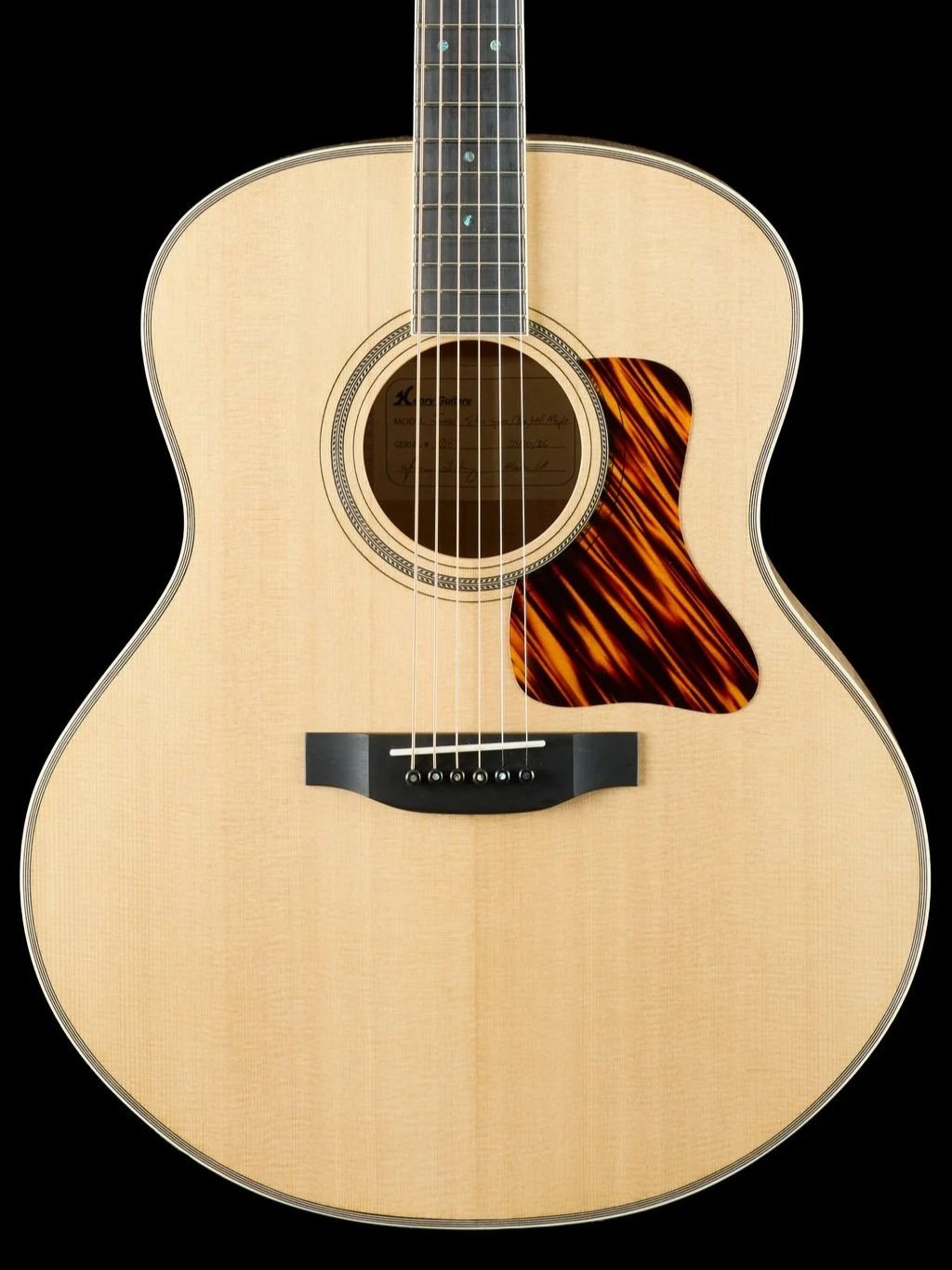 Close-up of an acoustic guitar with a natural wood finish, showing the soundhole, strings, and a tortoise shell pickguard on the right side.