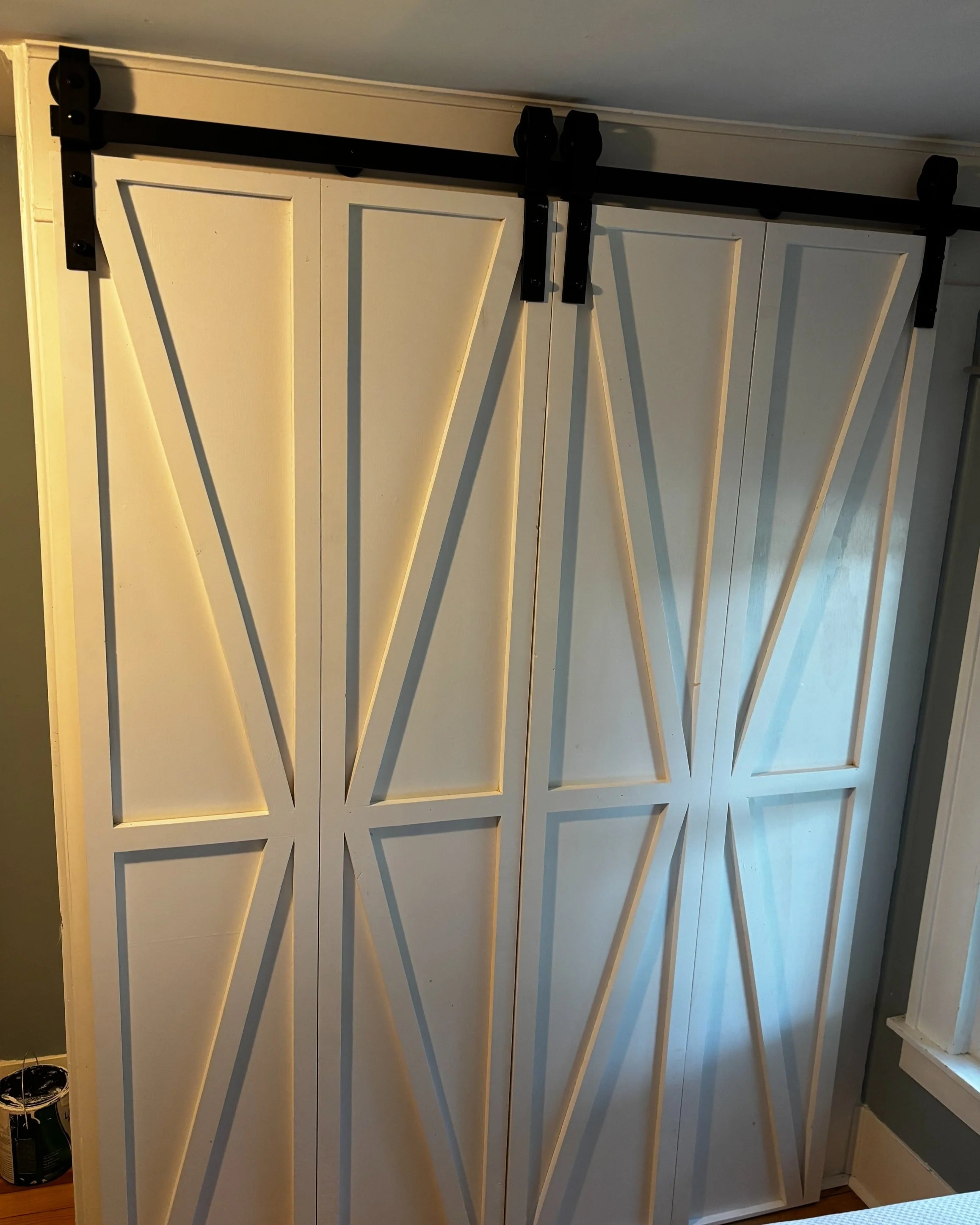 White sliding barn doors with black hardware and geometric panel design.