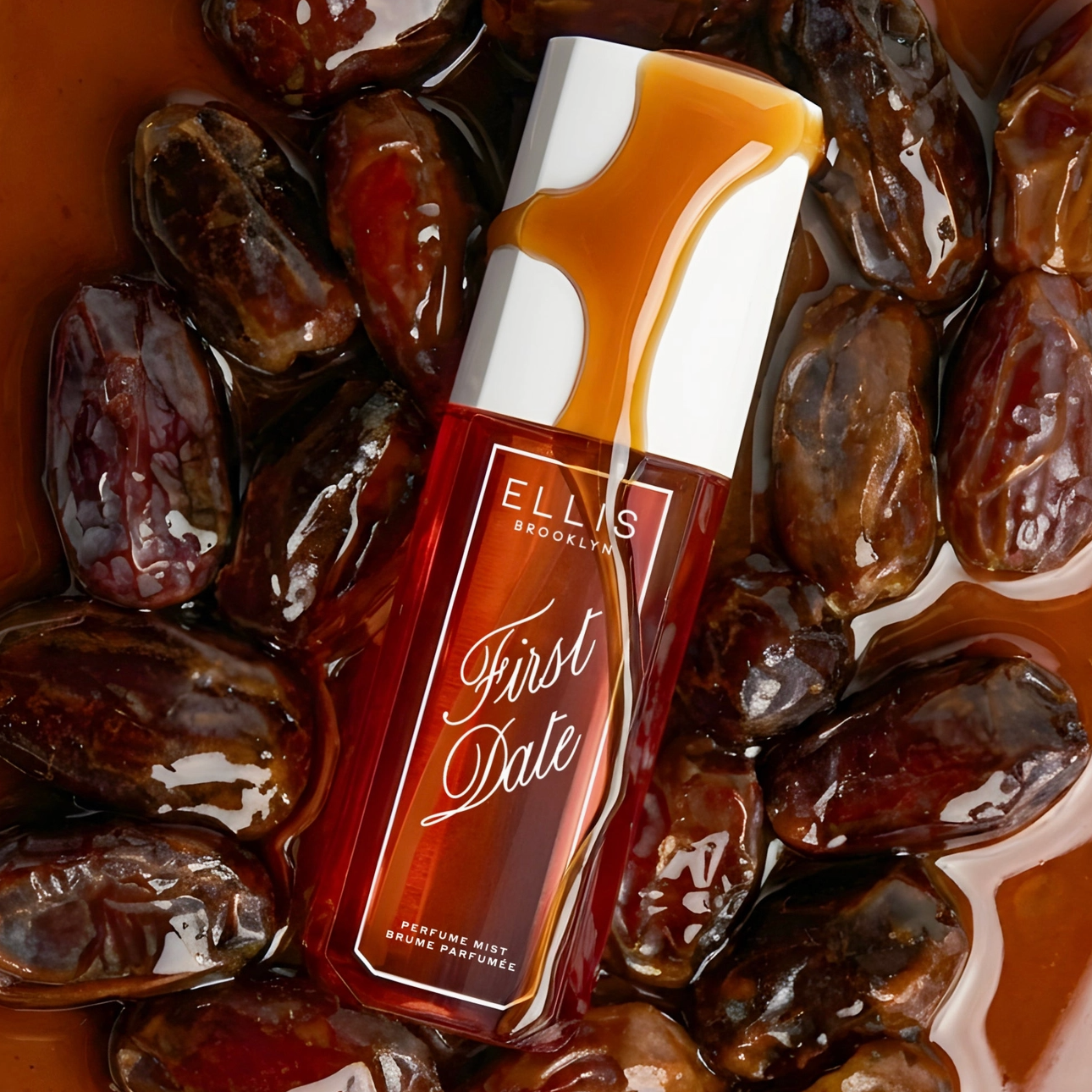 A bottle of Ellis Brooklyn First Date Perfume Mist sitting on dates with date syrup on top.