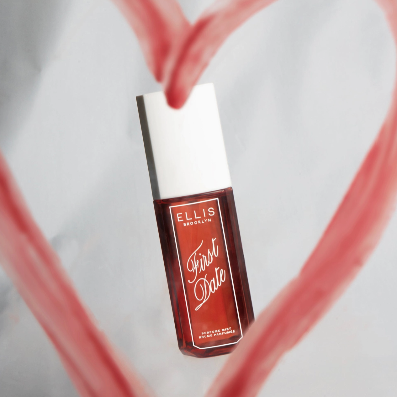 A bottle of Ellis Brooklyn First Date Perfume Mist shown in the middle of a lipstick heart.