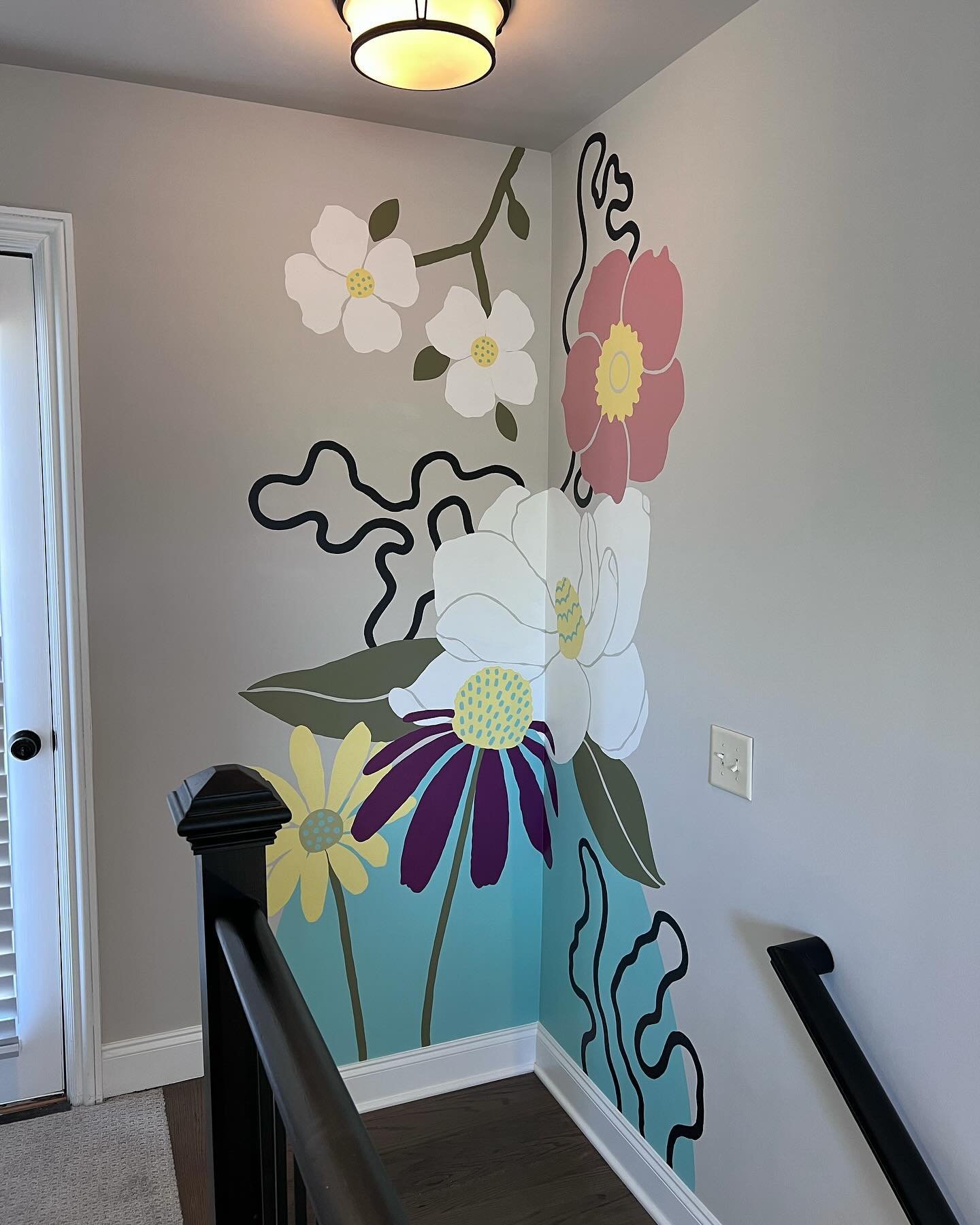 Murals don&rsquo;t have to be big to make an impact! This flower mural at the top of a stairway leads out to a rooftop floral mural of similar design. The mural is just visible from the lower level of the home, giving you a hint of the flowers above.
