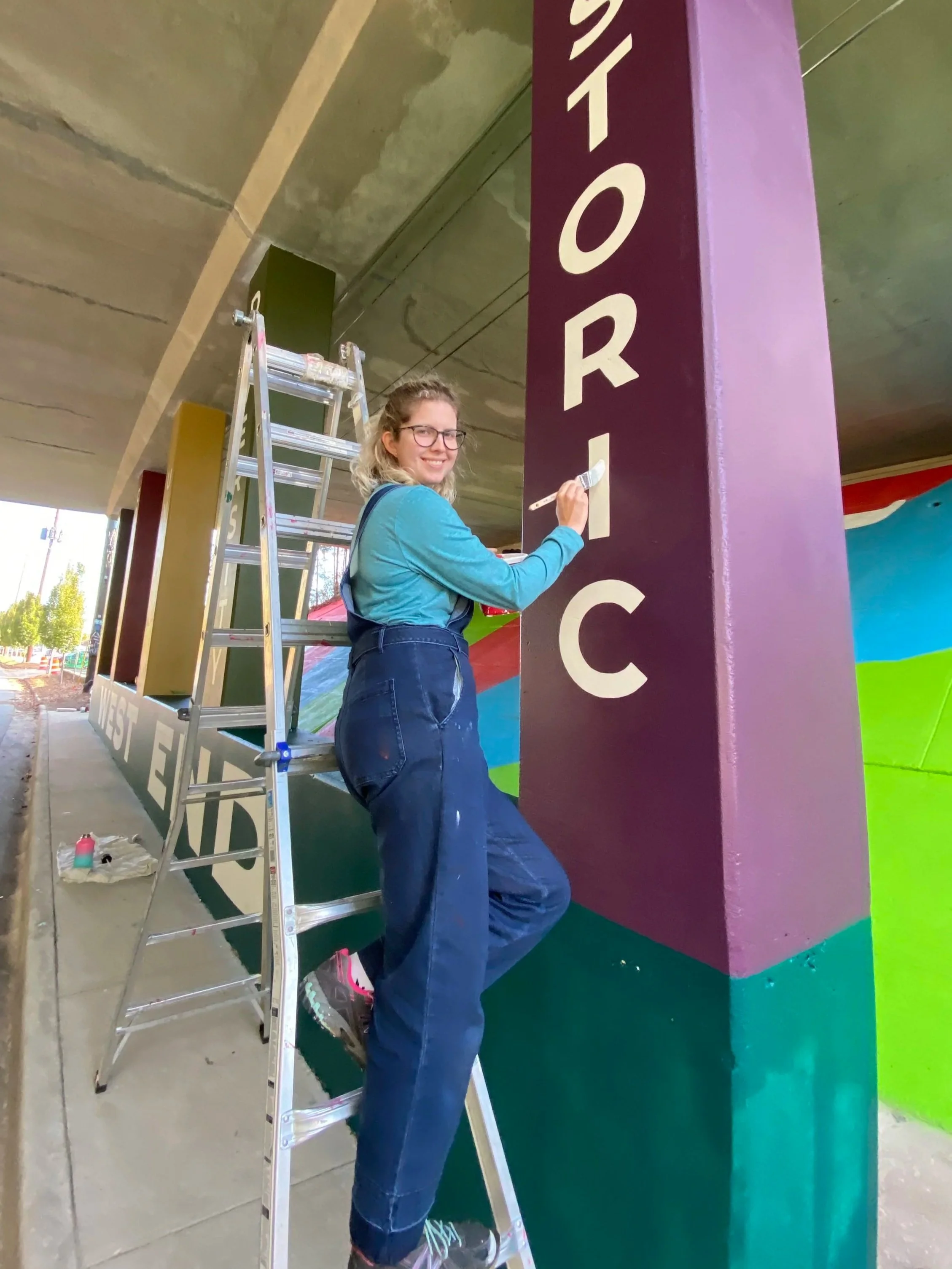 Elaine painting letters on a column.