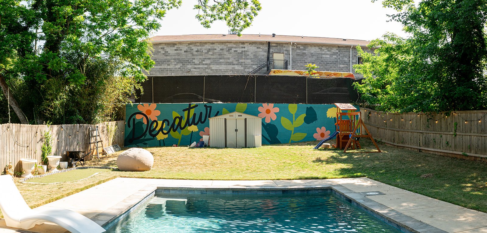Backyard residential mural in Decatur with flowers, leaves, a bird and butterfly. 2026
