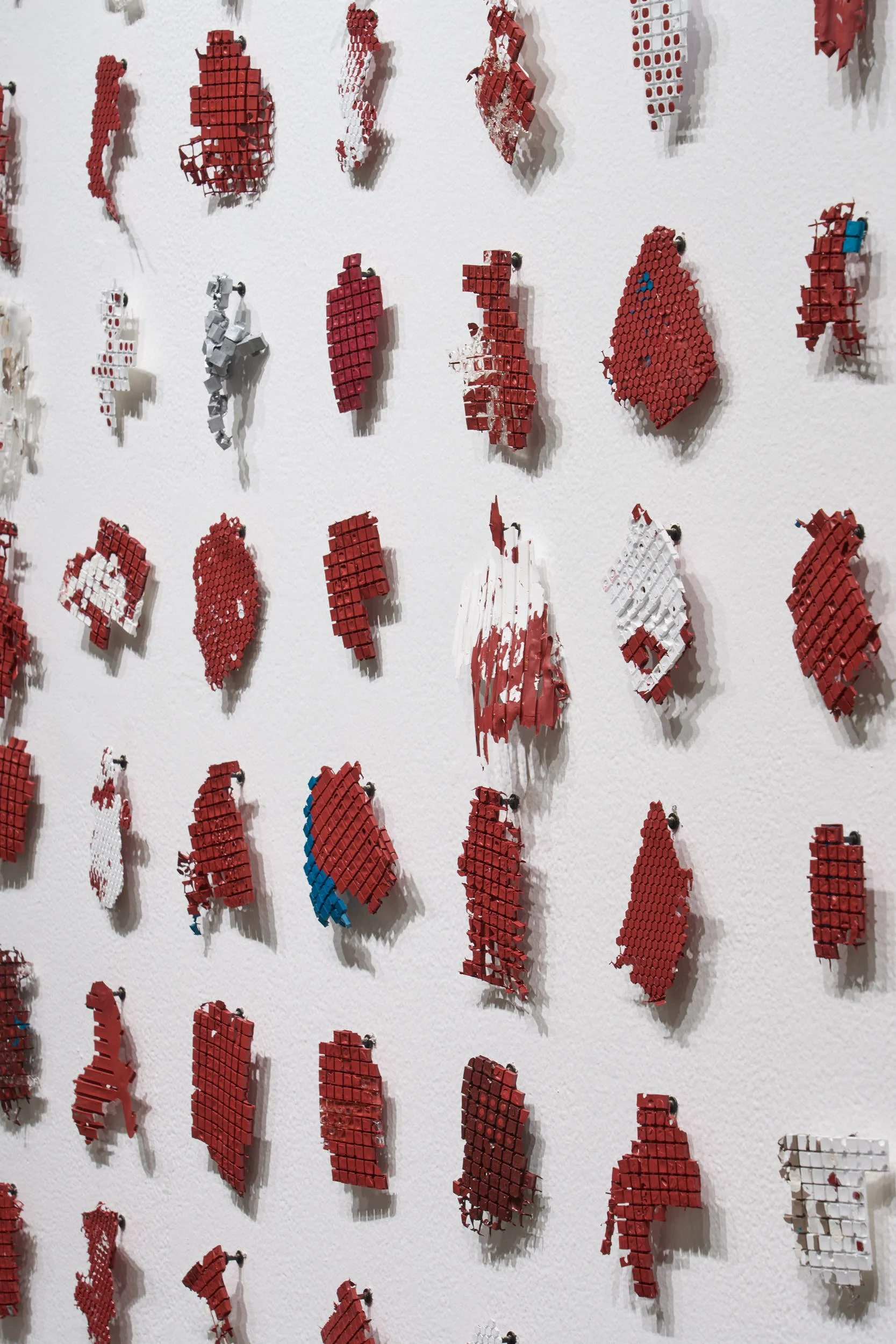 Detail of remnant pieces of paint arranged in a grid on the wall.