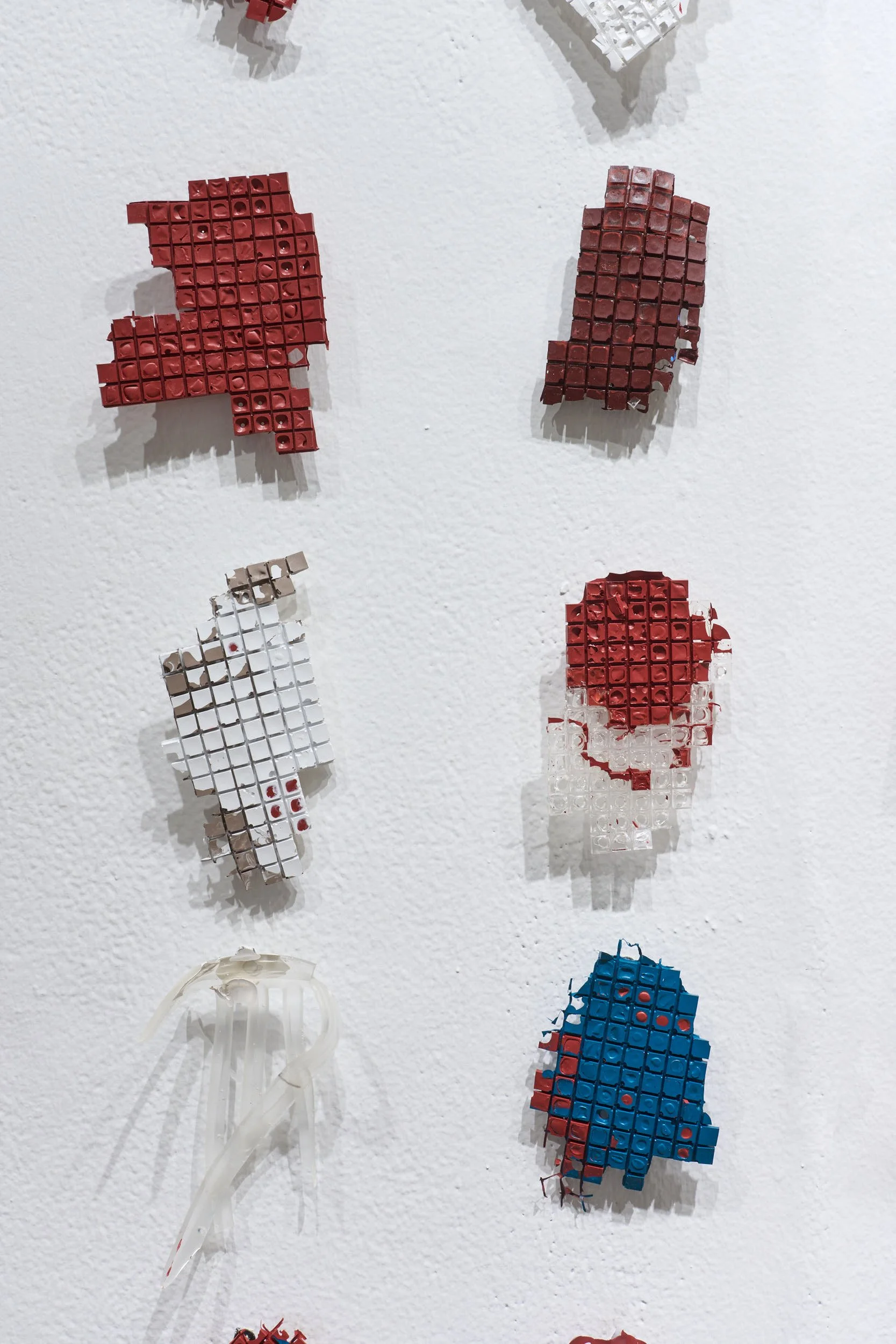 Detail of remnant pieces of paint arranged in a grid on the wall.