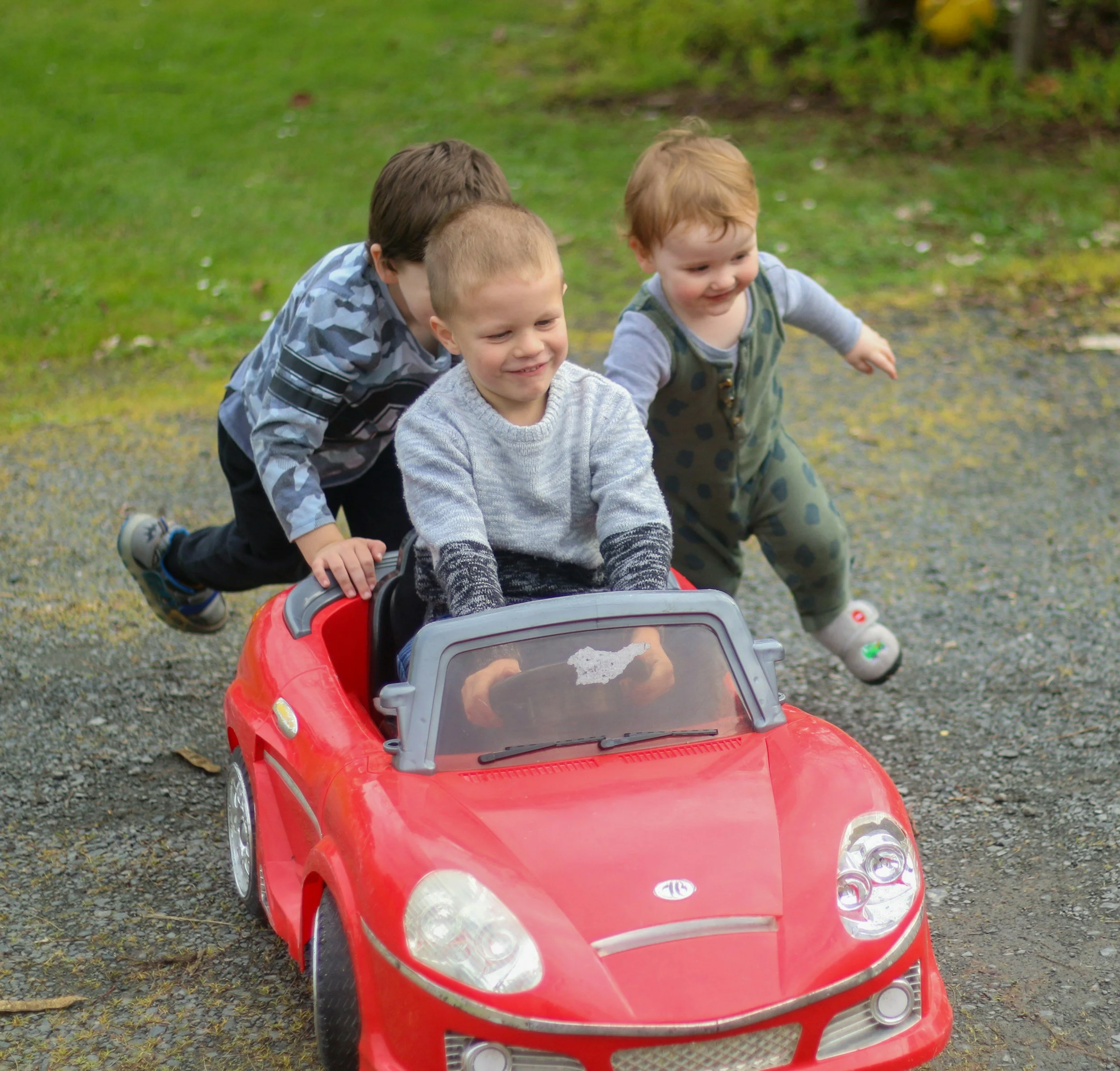 kids driving a toy car in an article about top tips for surviving a road trip with kids