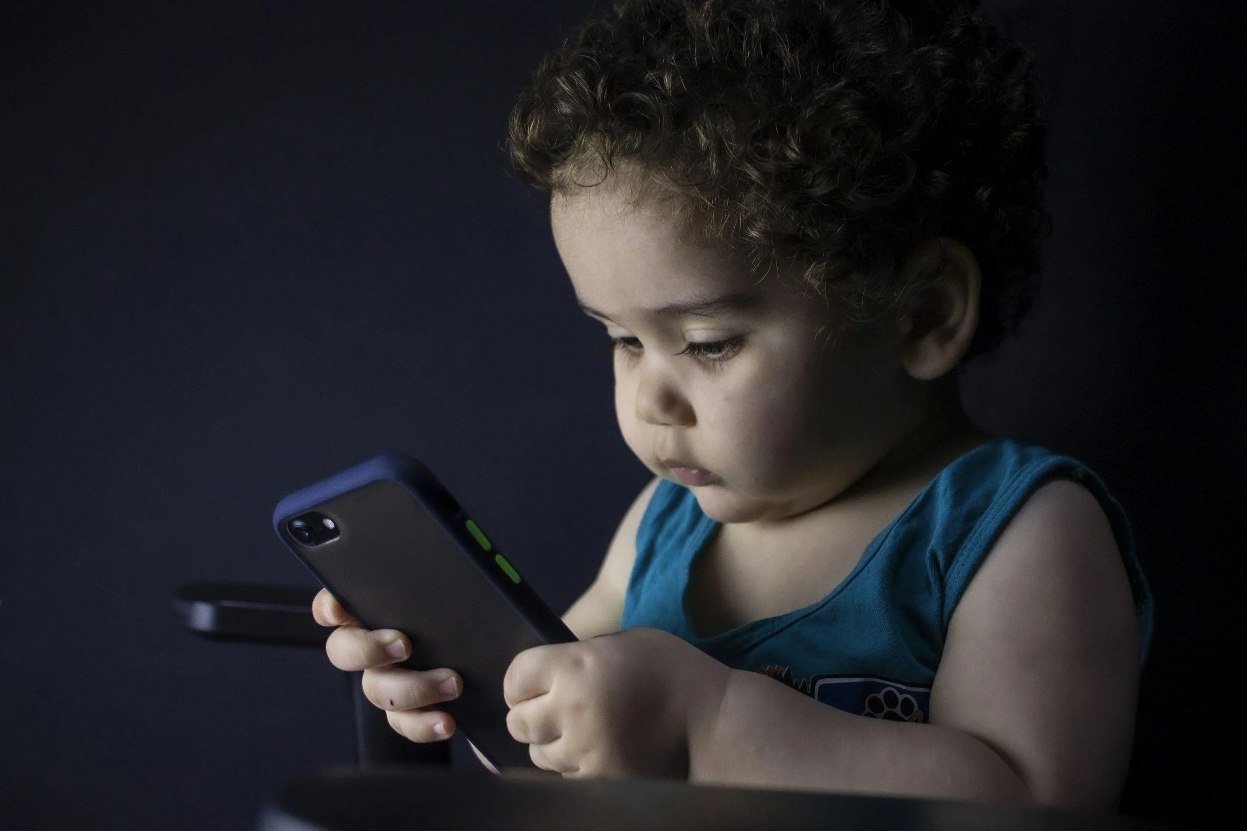 a baby holding a smart phone in a post about kids' screen time
