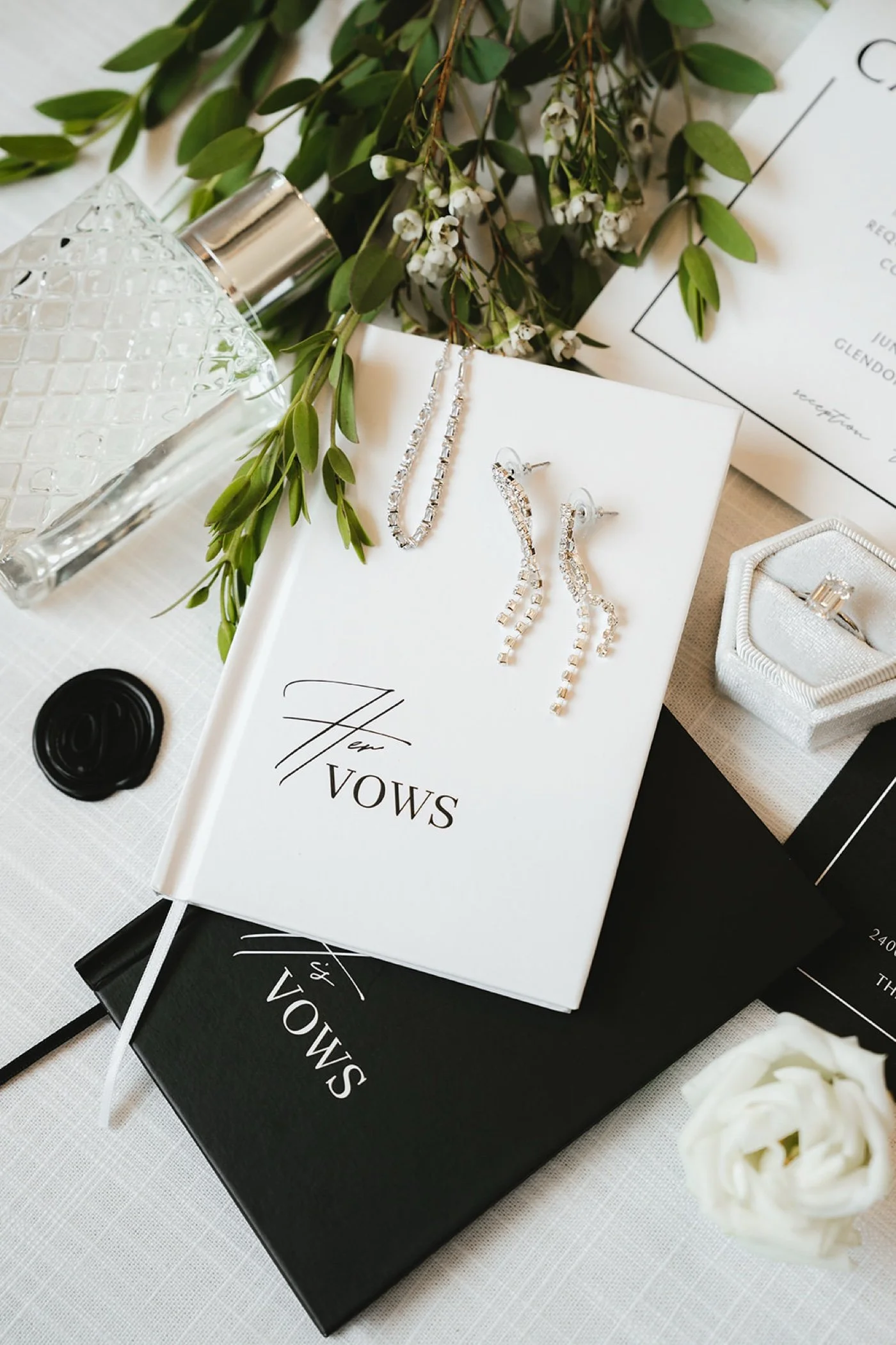 black and white wedding detail flat lay with vow books and silver jewelry