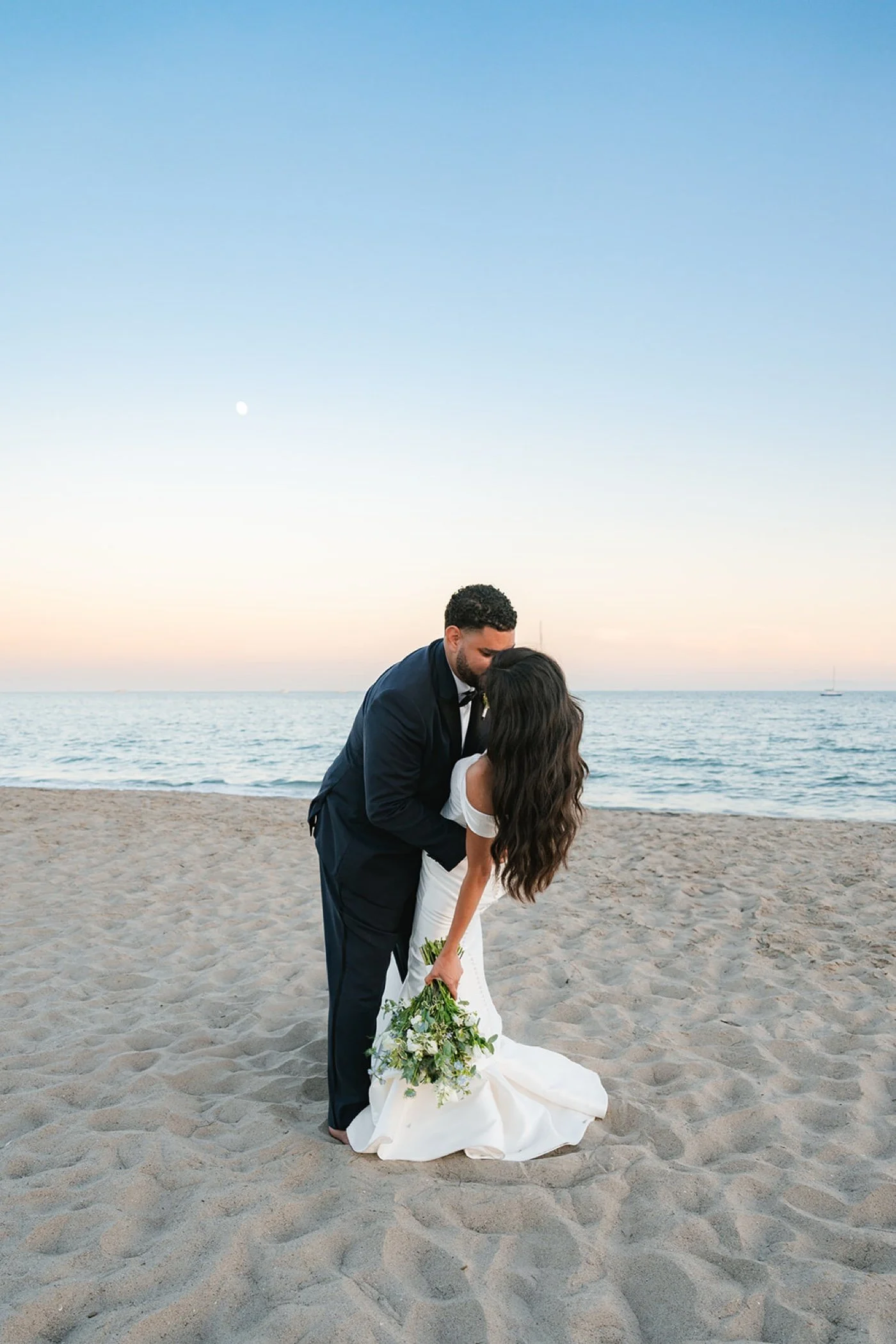bride and groom taking portraits on the beach at their cabrillo pavilion wedding in santa barbara