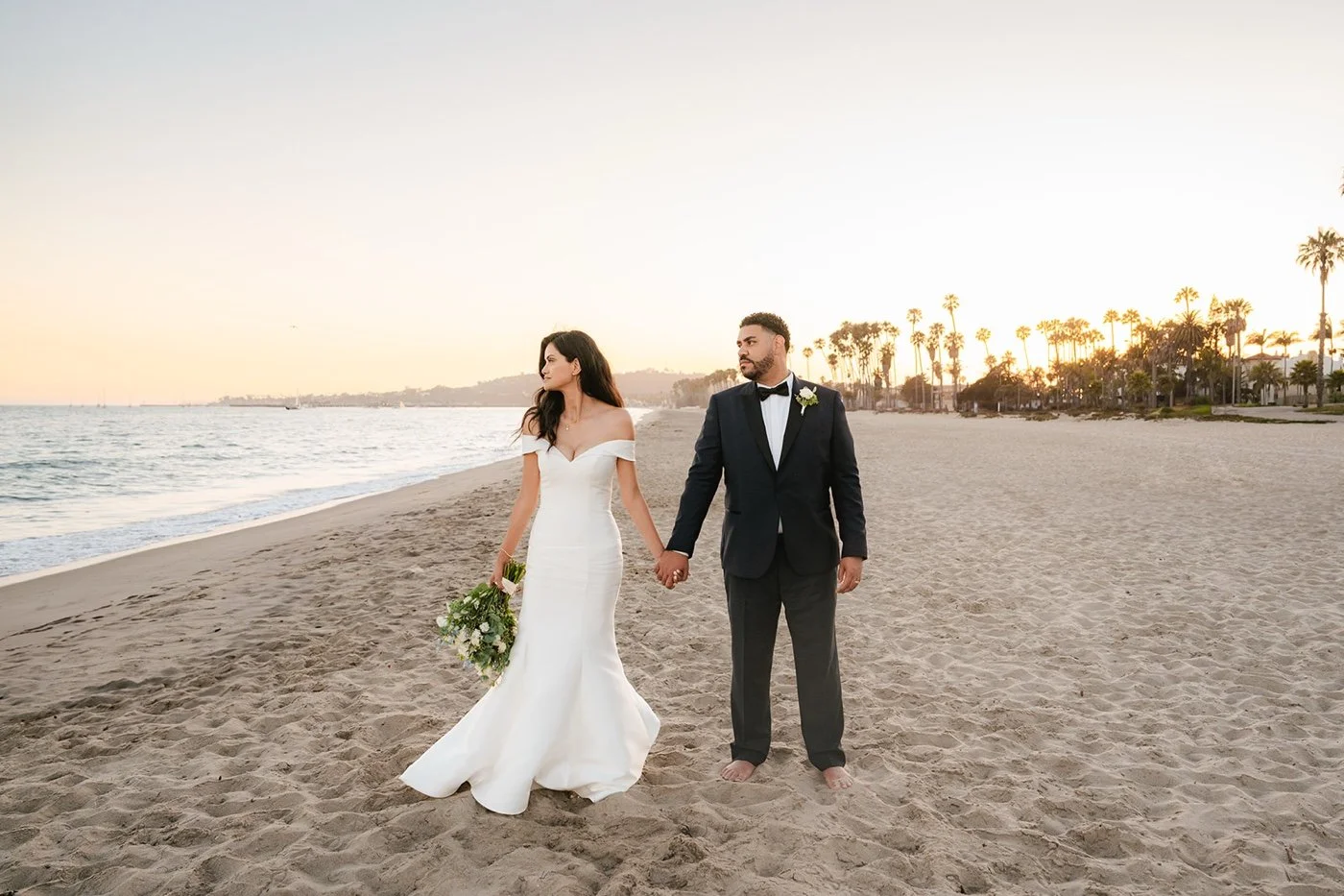 bride and groom taking portraits on the beach at their cabrillo pavilion wedding in santa barbara