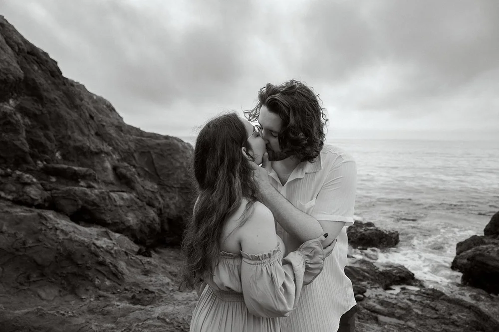 man kissing woman while taking engagement photos with ocean vies in Palos Verdes, California