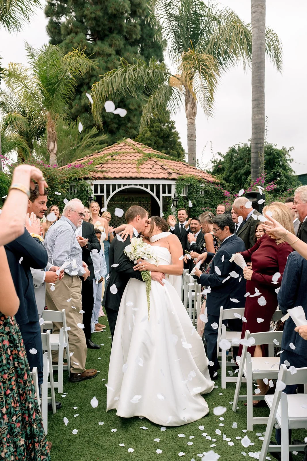 a bride and groom kissing while walking down the aisle at their los angeles wedding