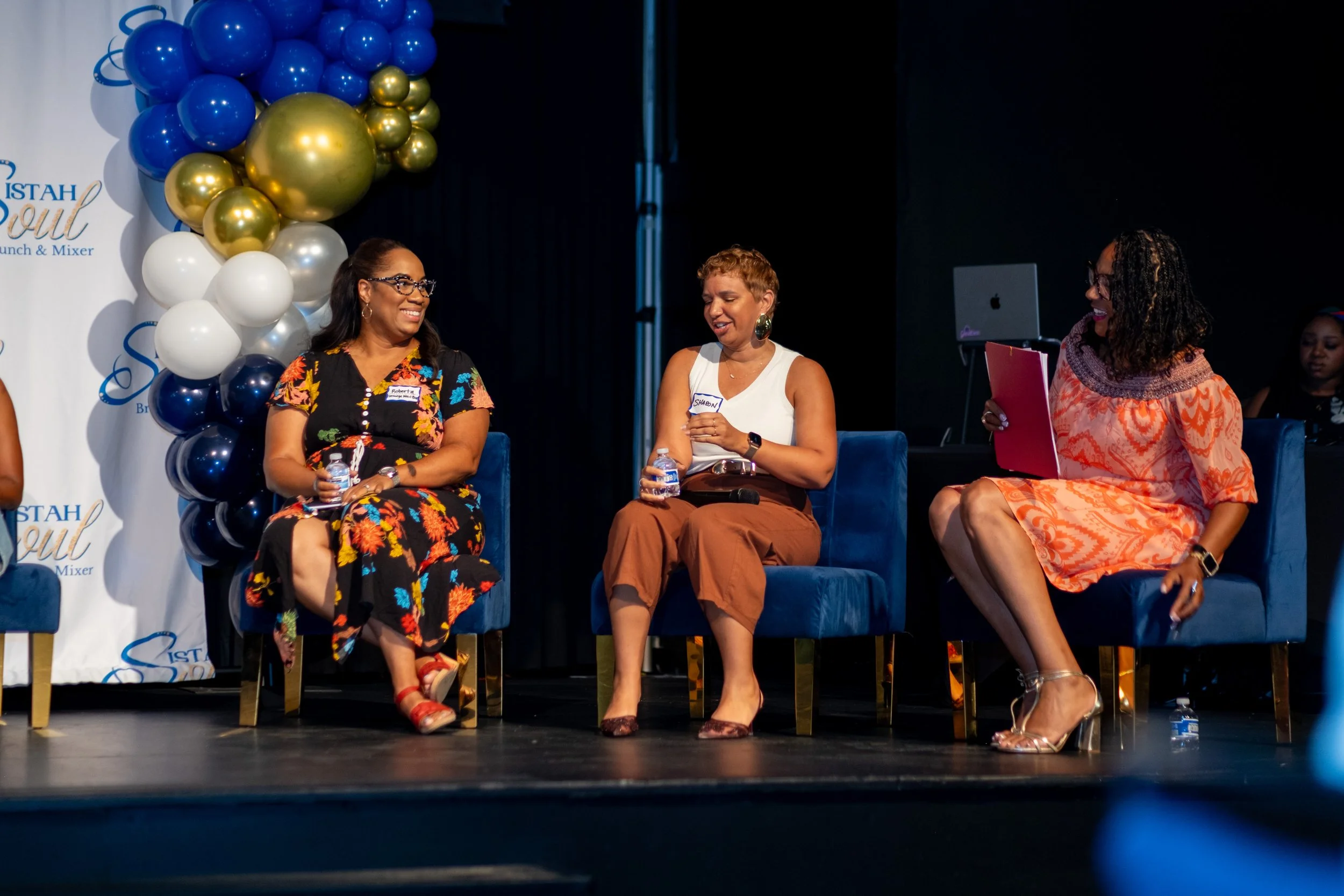 Three women sit on stage during a panel discussion.