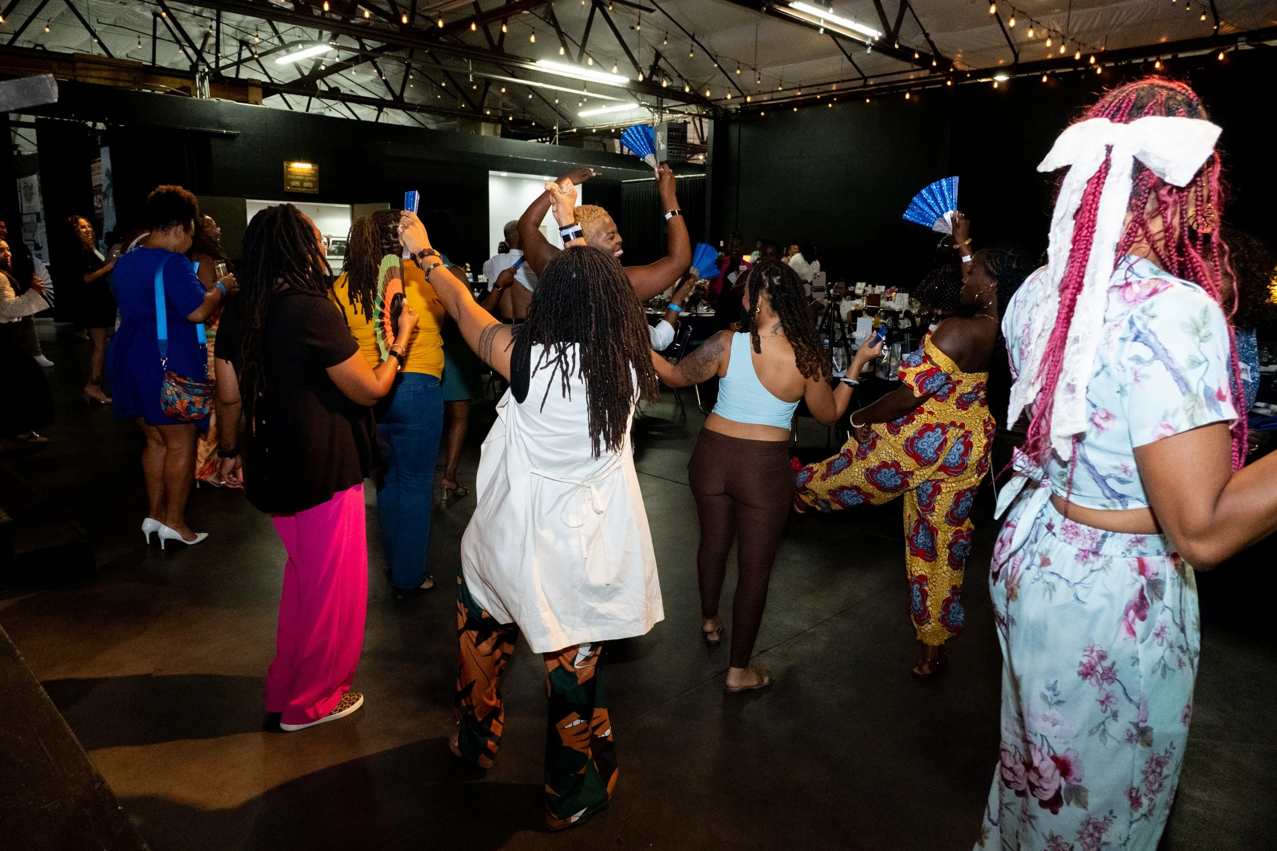 Attendees dance together and wave blue fans at the event.