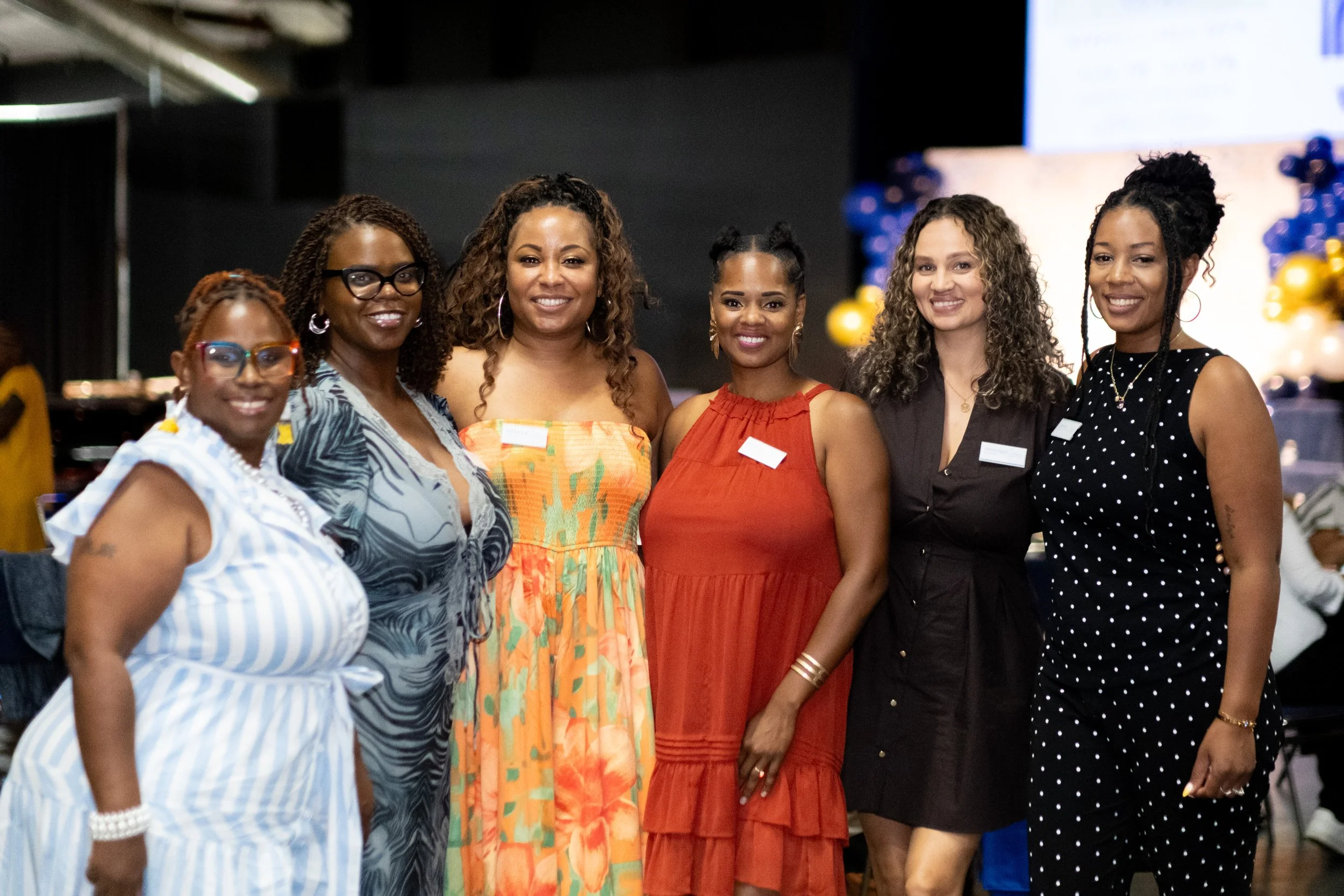 Six women pose together at the event.