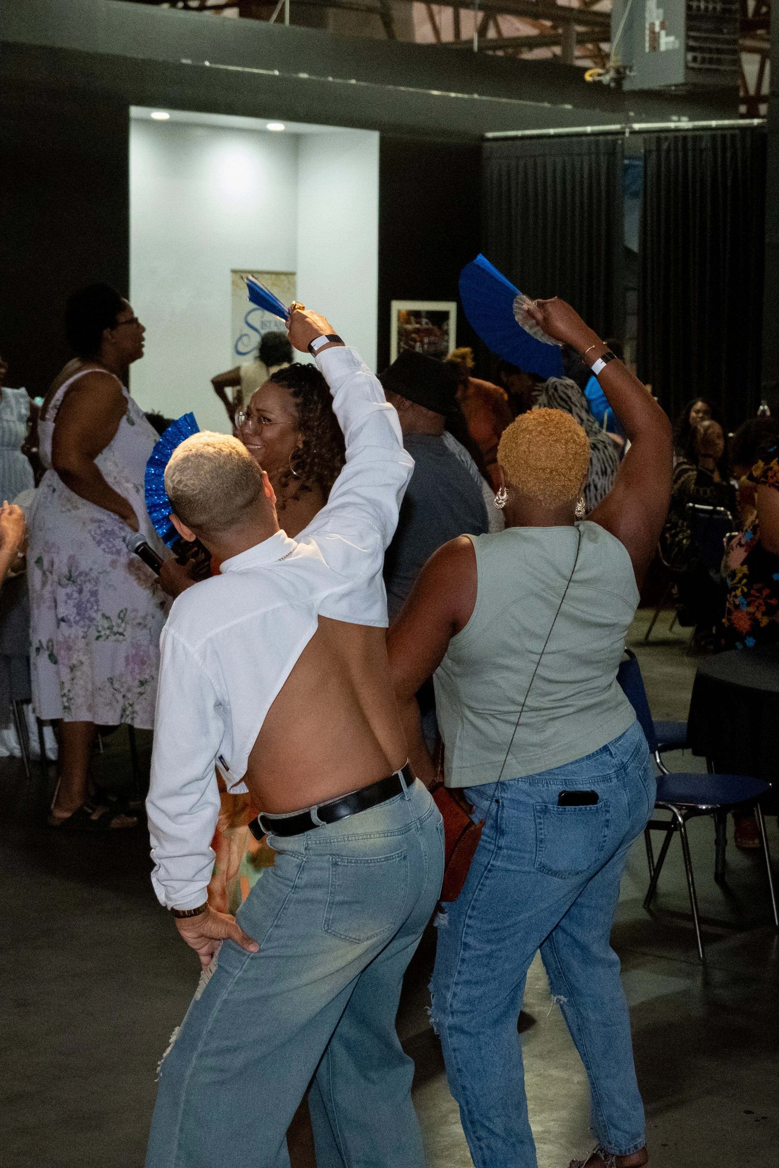 Guests dance and wave blue fans in the event space.