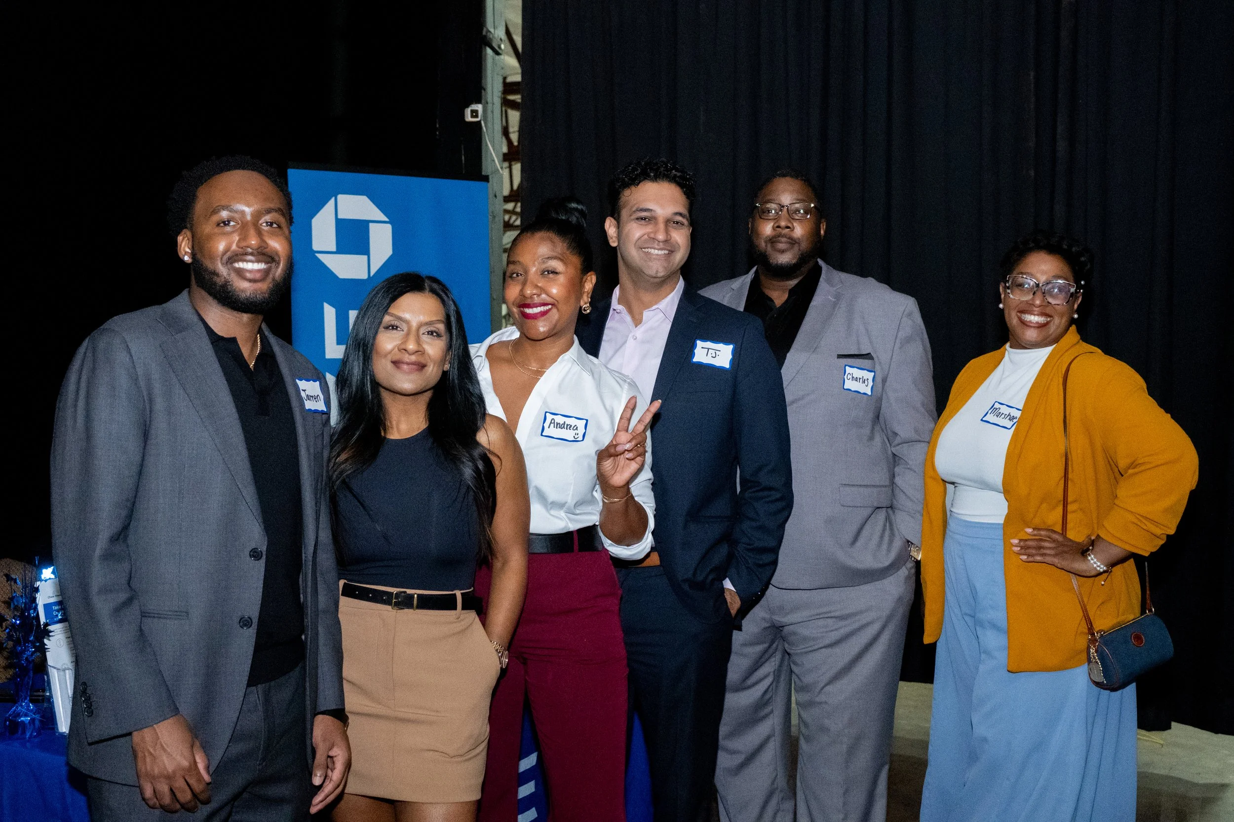 Six attendees pose together at the event, wearing name tags.