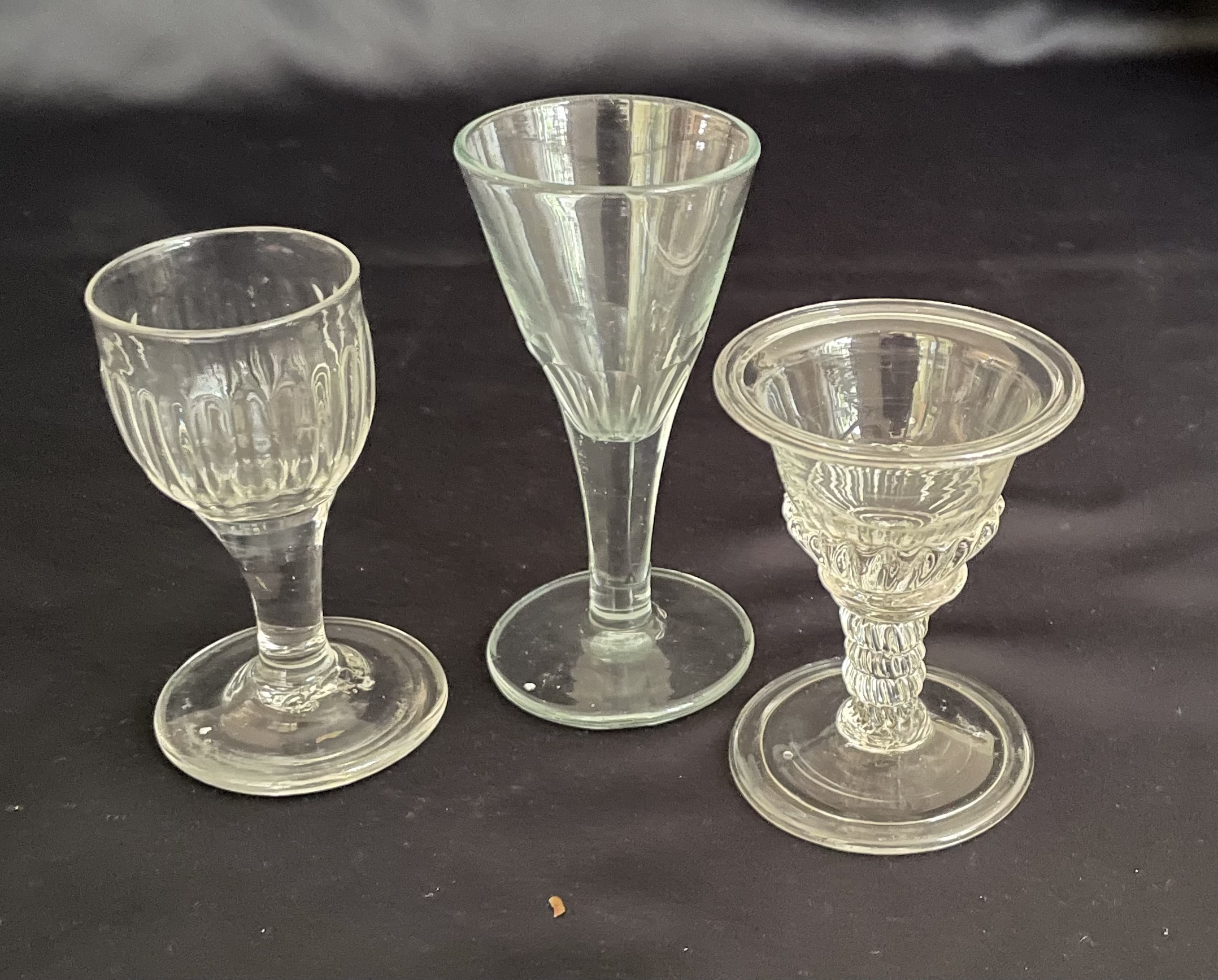 Set of three Toasting Glasses:
Ogee Shaped ribbed Bowl over Clear Stem and Rough Pontil,
Trumpet Shaped Bowl,
Moulded Stem and Base of Bowl Folded Rim and Foot