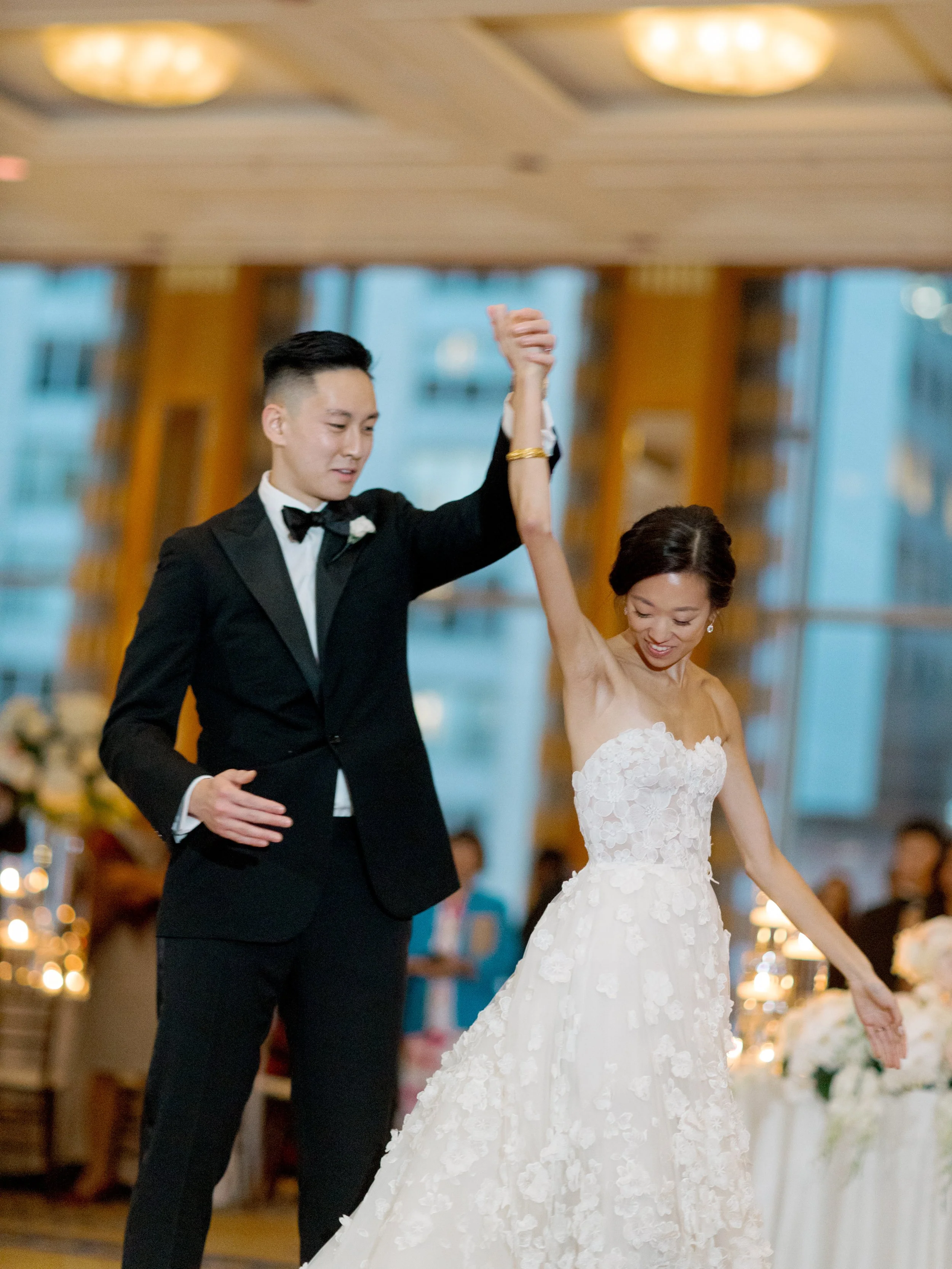 Groom spins the bride under his raised arm during the first dance on The Peninsula Chicago ballroom floor