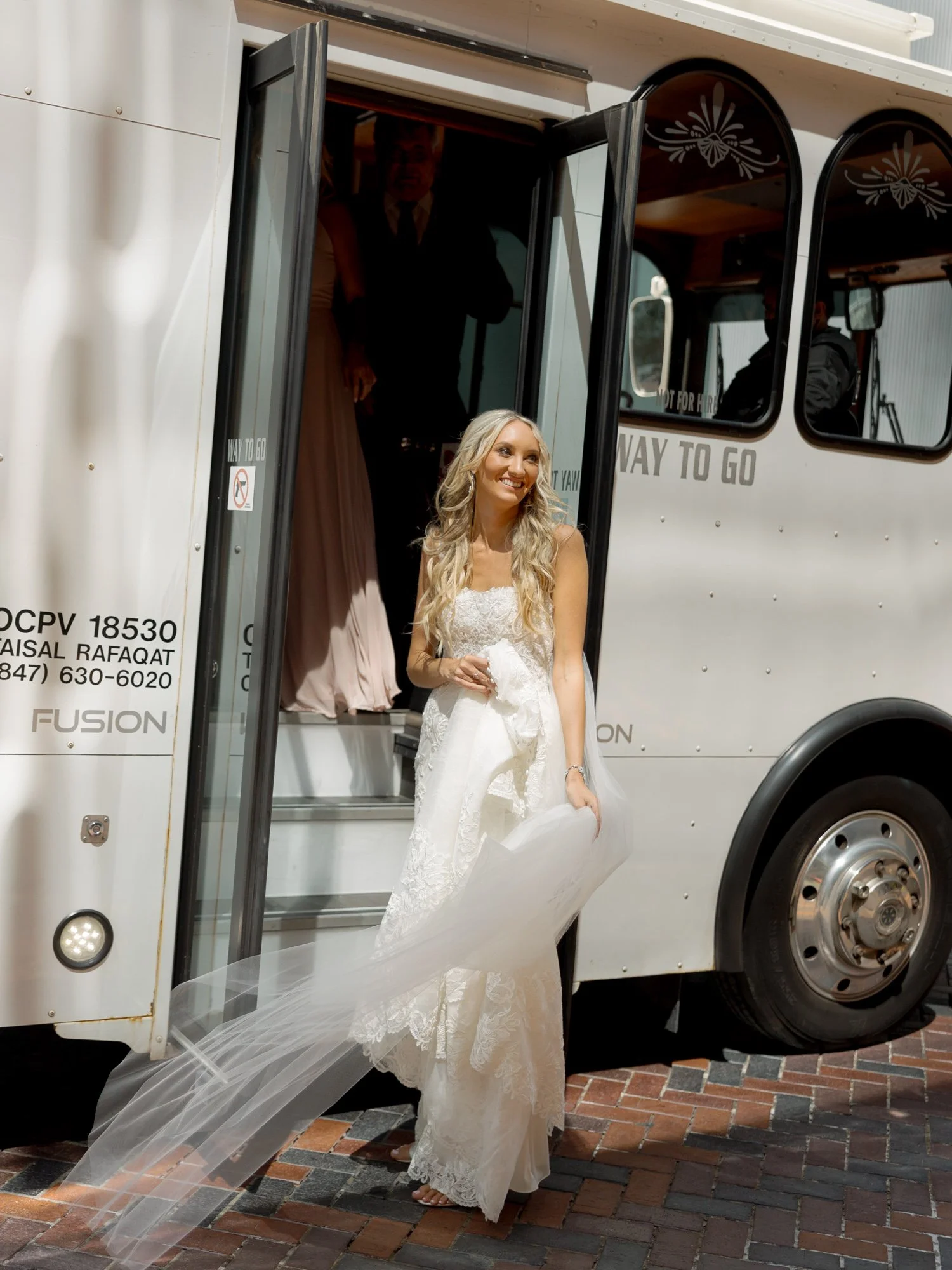 The bride steps off the wedding trolley with a beaming smile, her lace gown and flowing veil trailing behind her as she arrives at the Chicago Illuminating Company.